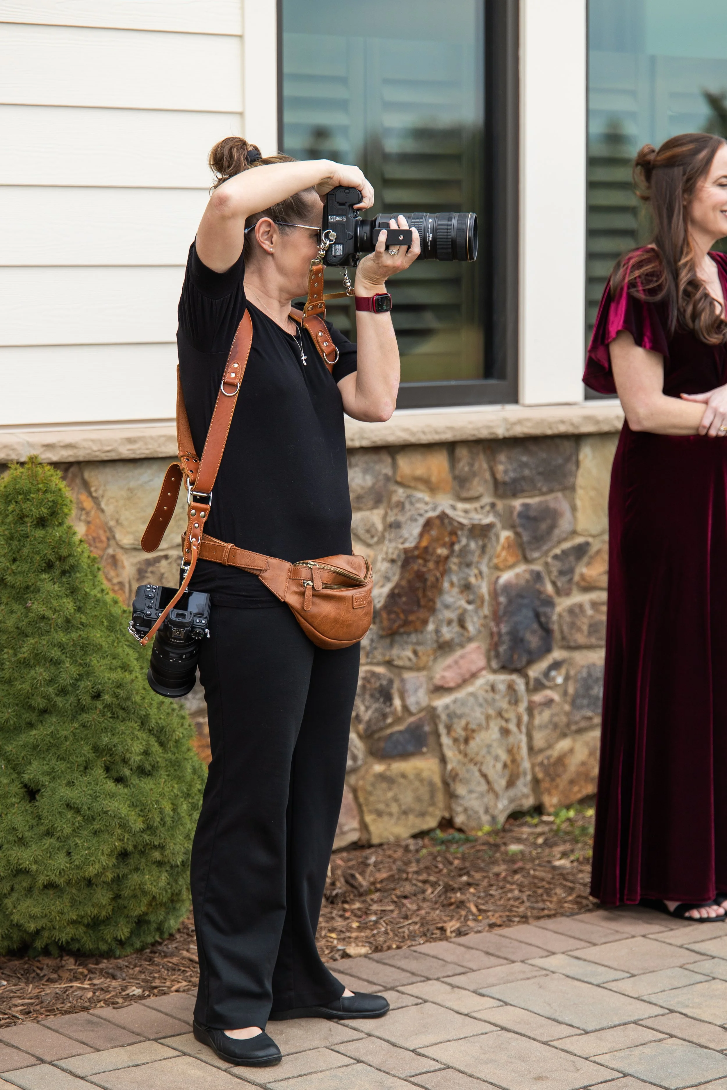 wedding photographer with camera harness and camera, photographing a bridal party