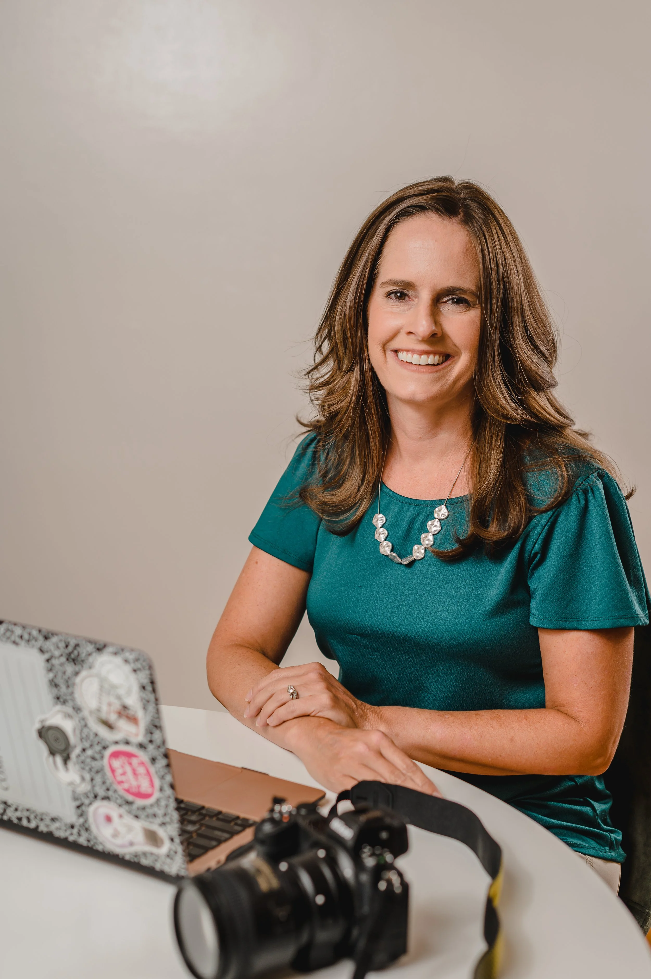 Kimberly Cauble, educator and photographer, sits at her laptop and with a camera nearby