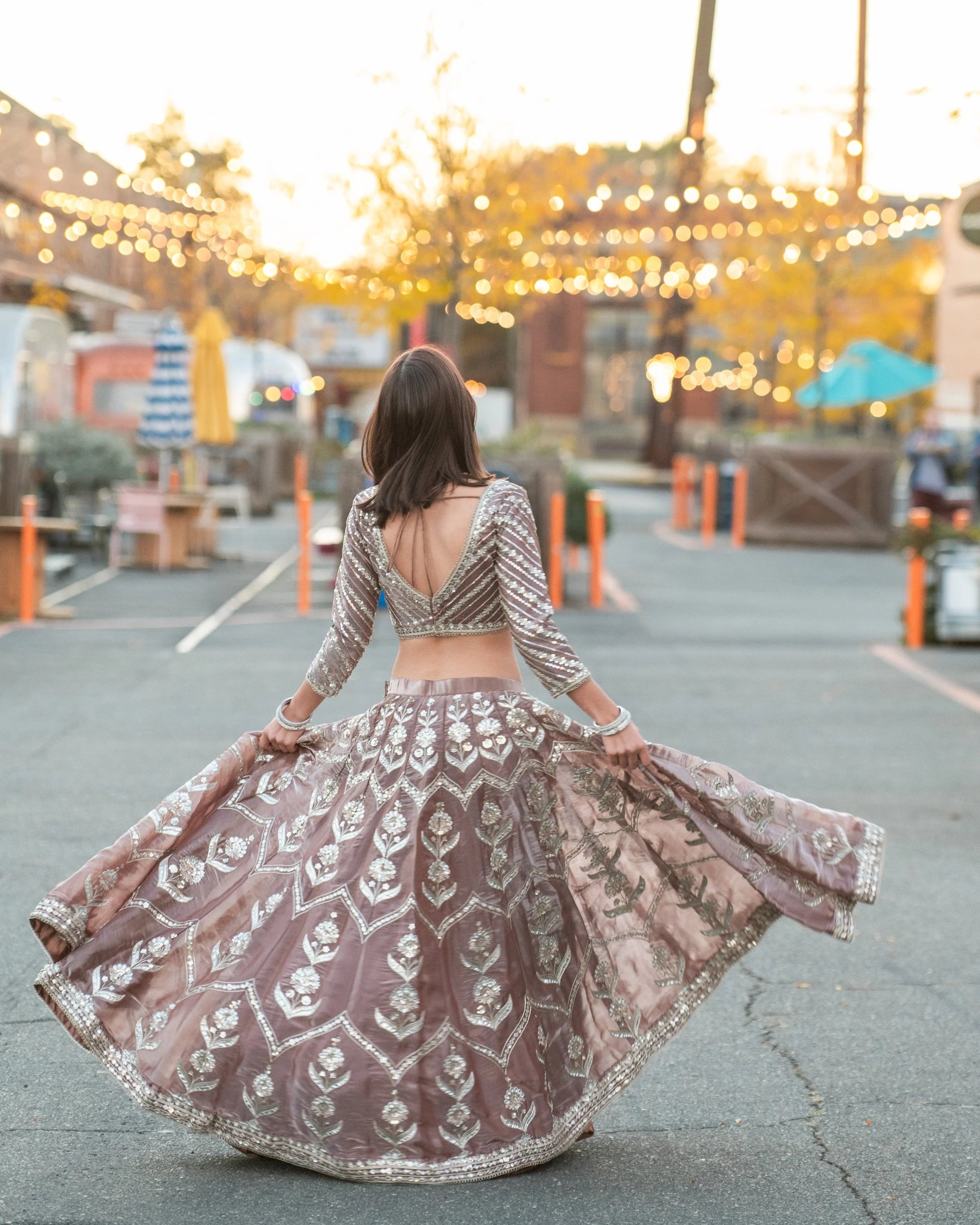 a senior girl twirling in an Indian dress in front of twinkle lights at Camp North End in Charlotte, NC