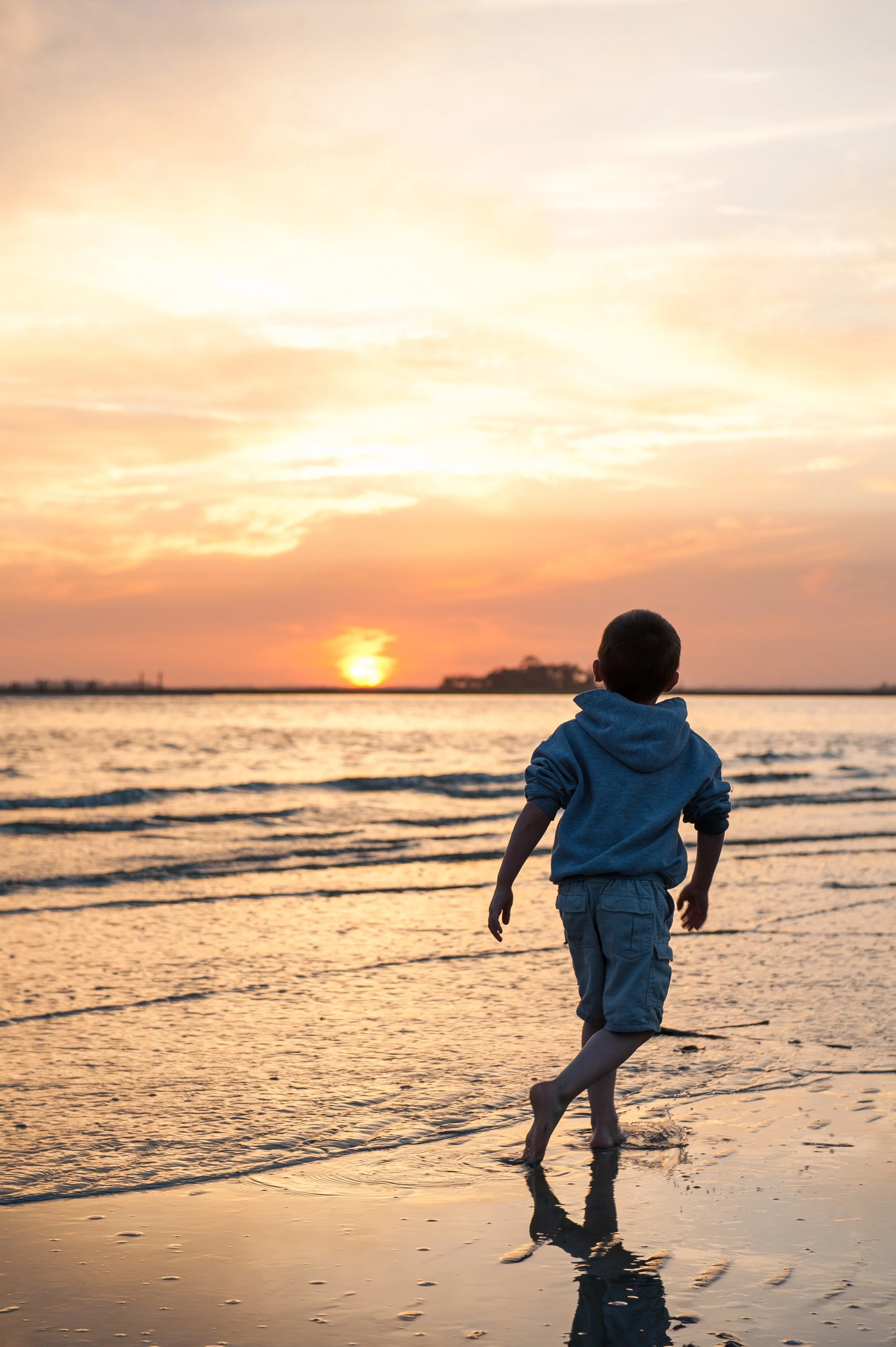 A young boy runs along the shoreline at the point of Fripp Island as the sun sets.