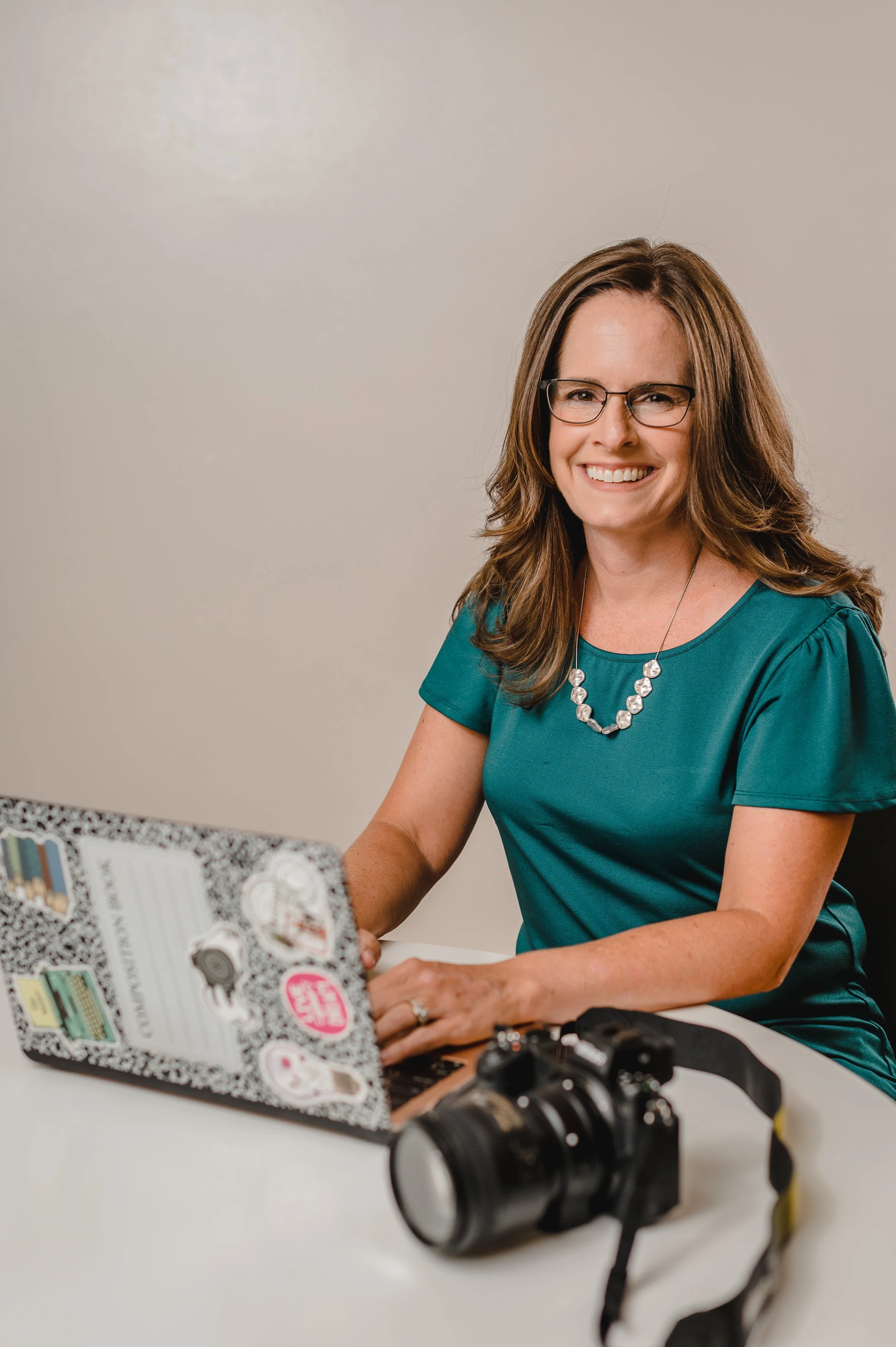 Photo of a photographer sitting behind a computer and smiling, camera nearby