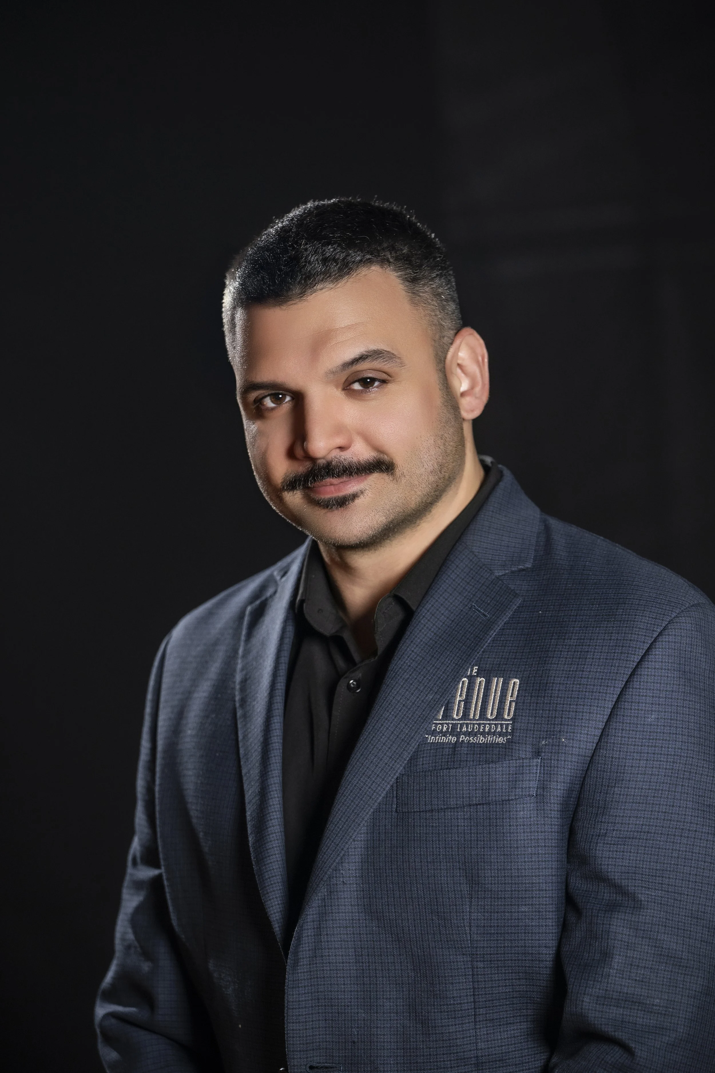 Man in blue suit and black shirt against dark background