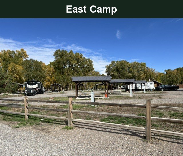 East Camp RV sites and covered shelters behind a split-rail fence at Woods and River RV Park.