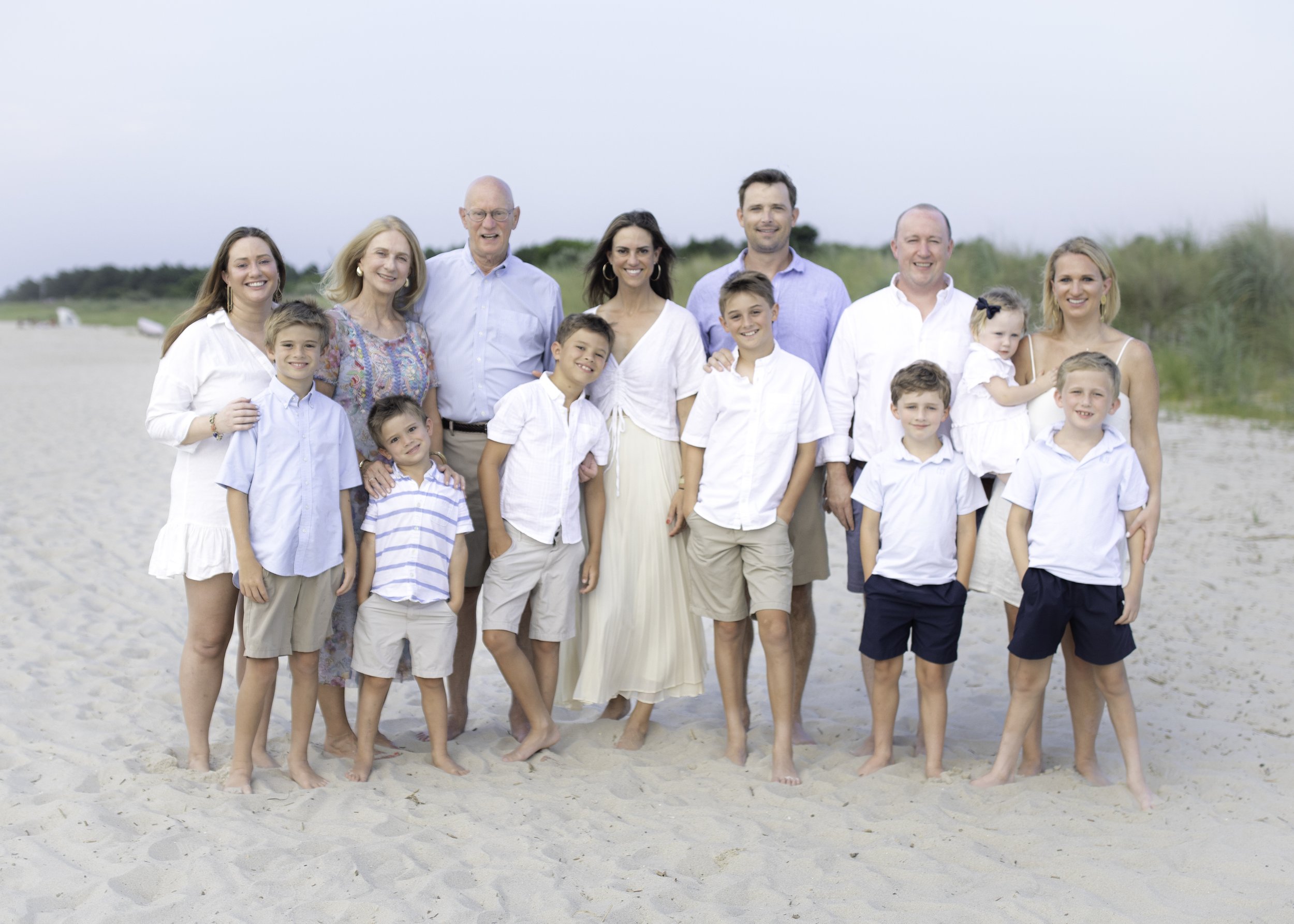 Family group on the beach wearing casual summer clothing.