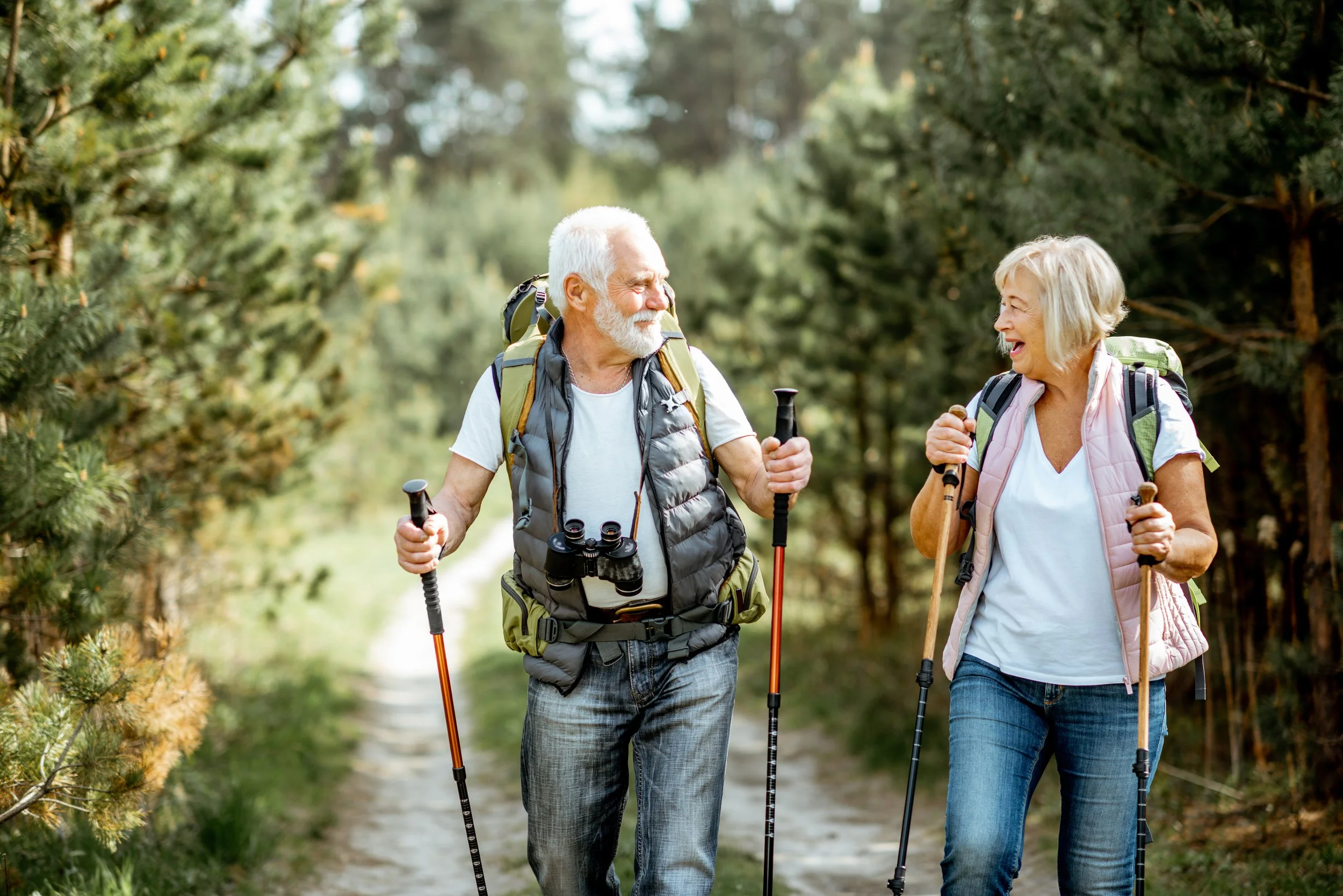 Senior couple with walking sticks going on a hike.
