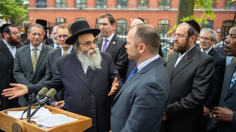 Rabbi David Niederman, executive director of the United Jewish Organization of Williamsburg, center left, joins City Council Speaker Corey Johnson, center right, in Brooklyn on Monday. Photo Credit: Corey Sipkin