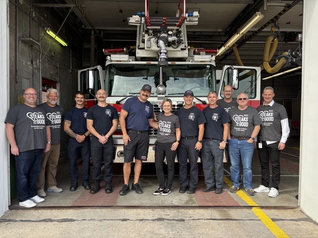 A group of first responders pose in front of a fire truck.