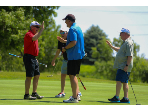 Four golfers high five at a golf fundraiser, the top charity fundraising idea.