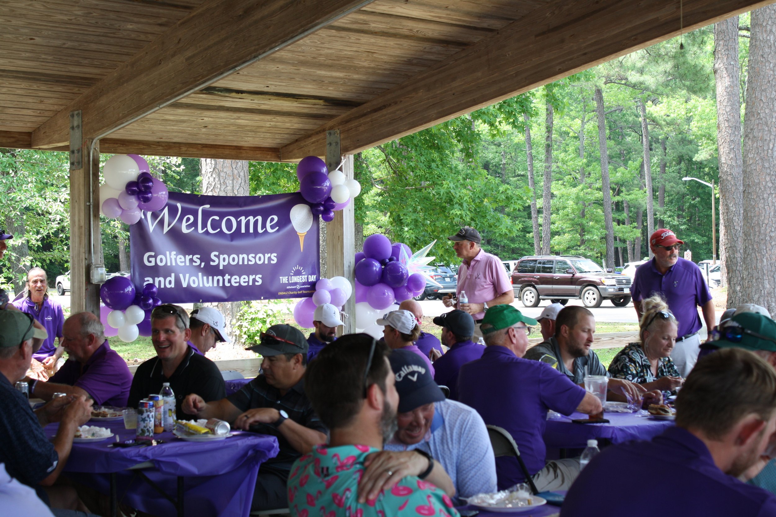 People wearing purple shirts gather at a charity golf tournament organized by a chaptered nonprofit.