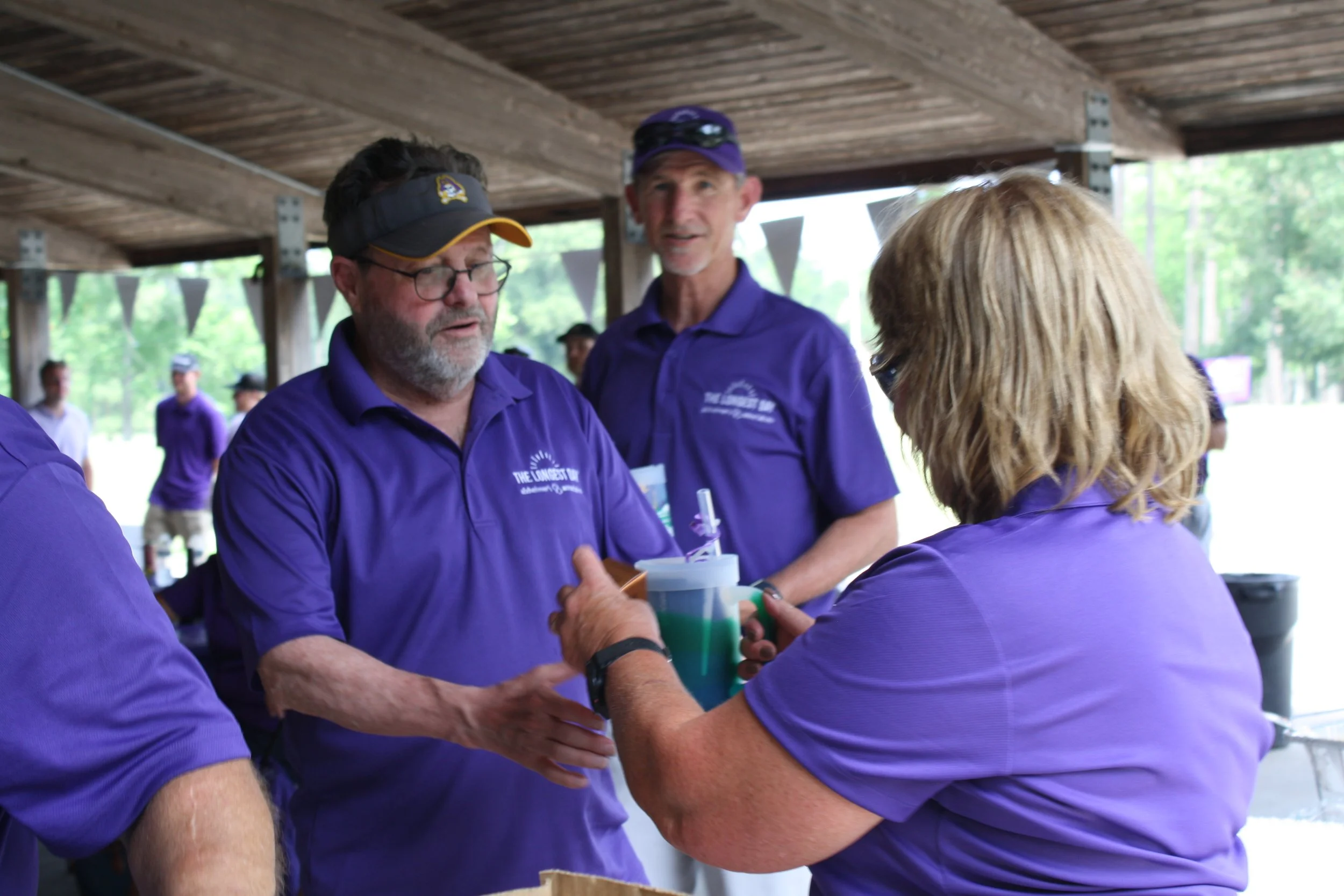 People wearing purple shirts at a charity golf tournament organized by a chaptered nonprofit.