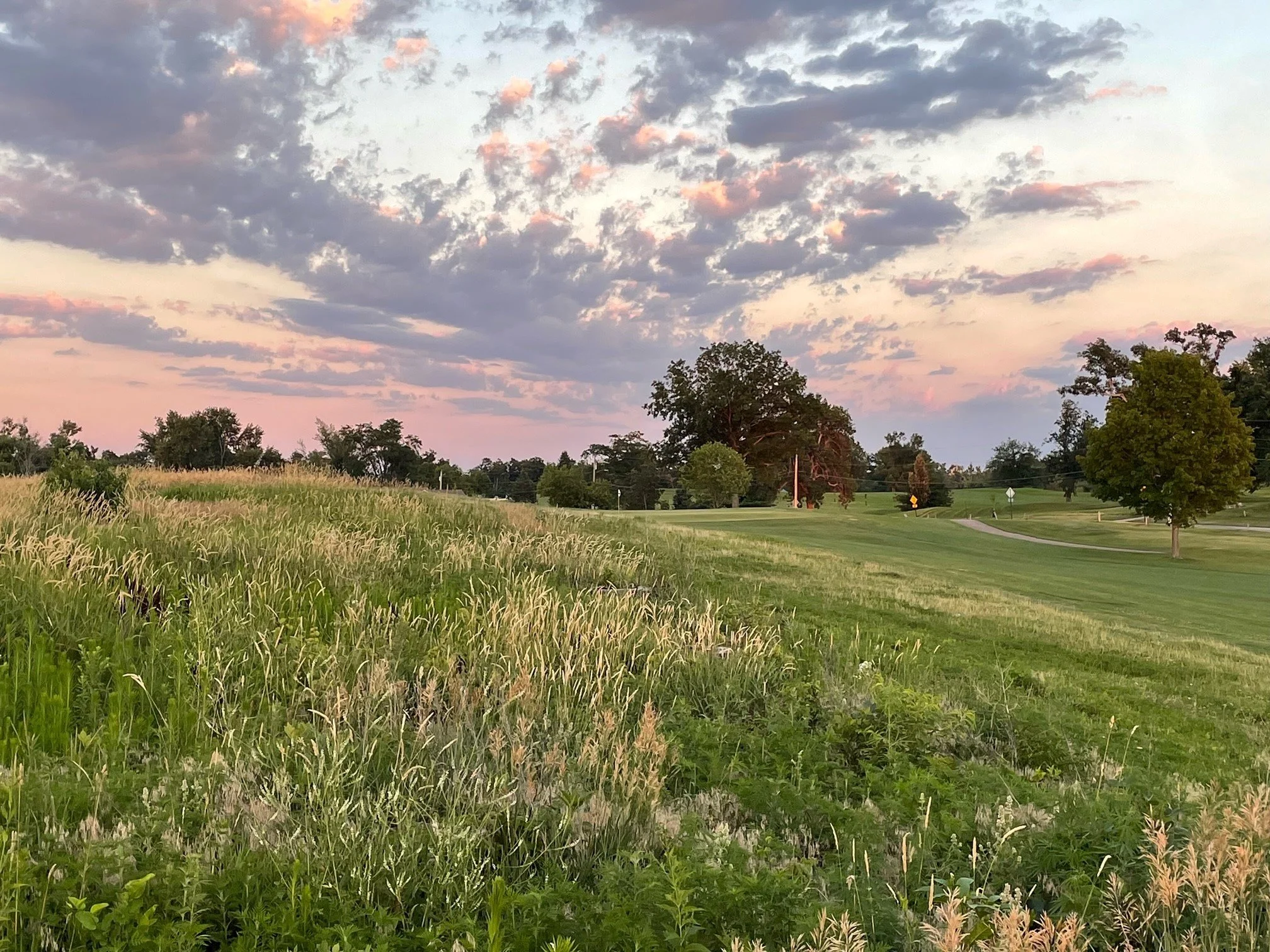 A golf course set against clouds and a setting sun.