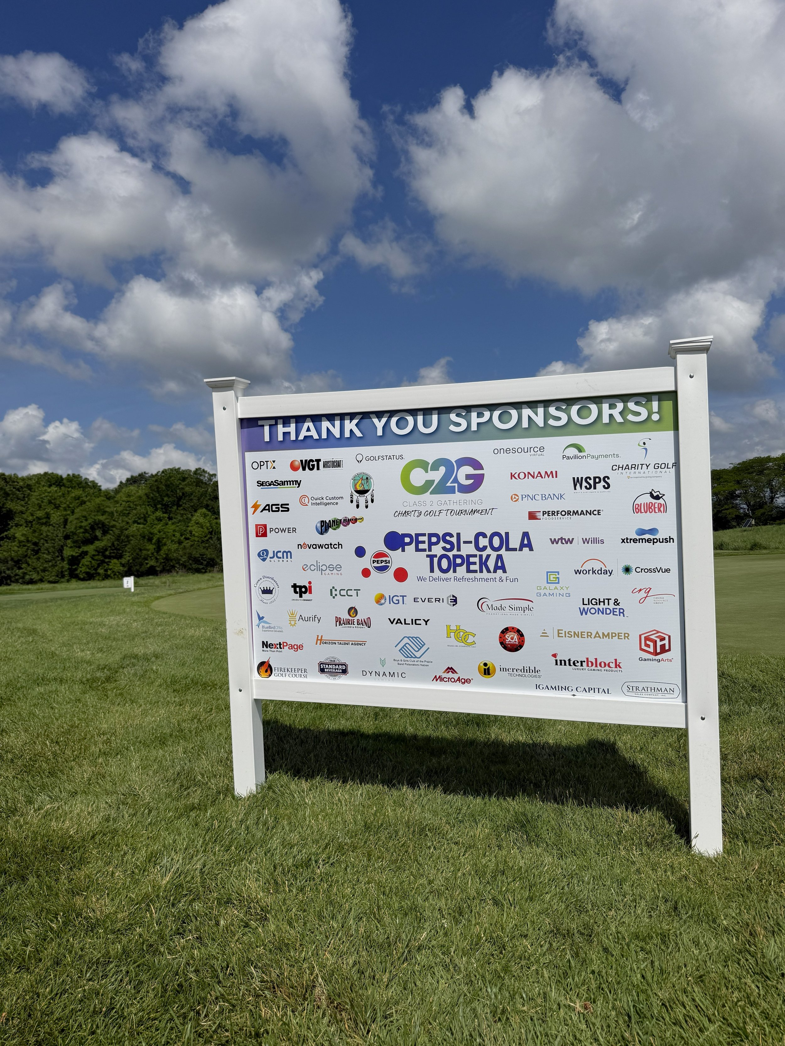 A sign is posted on a golf course recognizing sponsors for the Class 2 Gathering Golf Tournament.