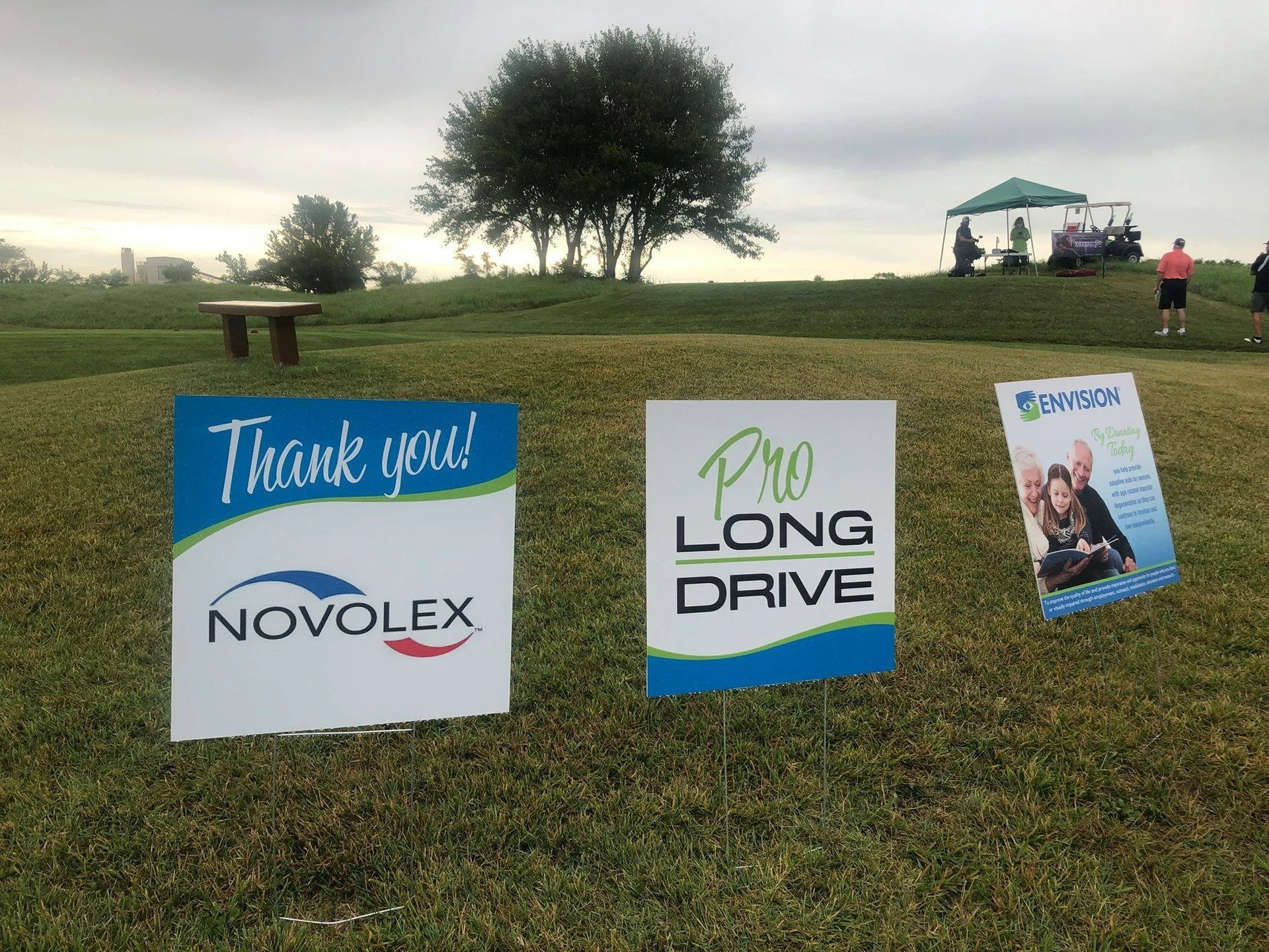 Signs recognizing the sponsors of a long-drive entertainer at a golf fundraiser.