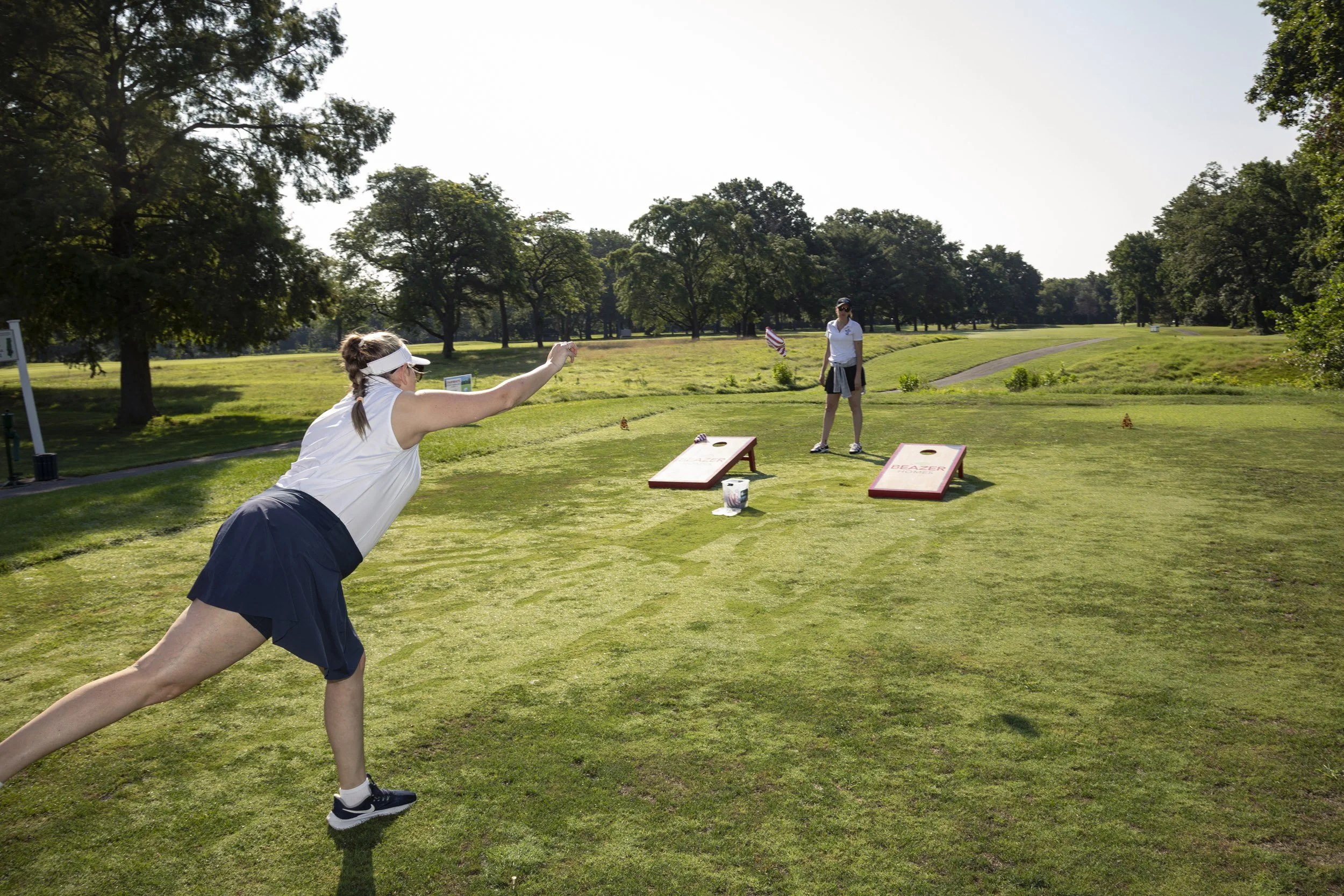Two female golfers throw cornhole bags at the charity golf tournament.