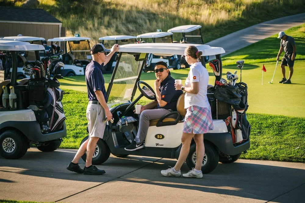 Three golfers chat before the start of a golf clinic at a charity golf tournament.