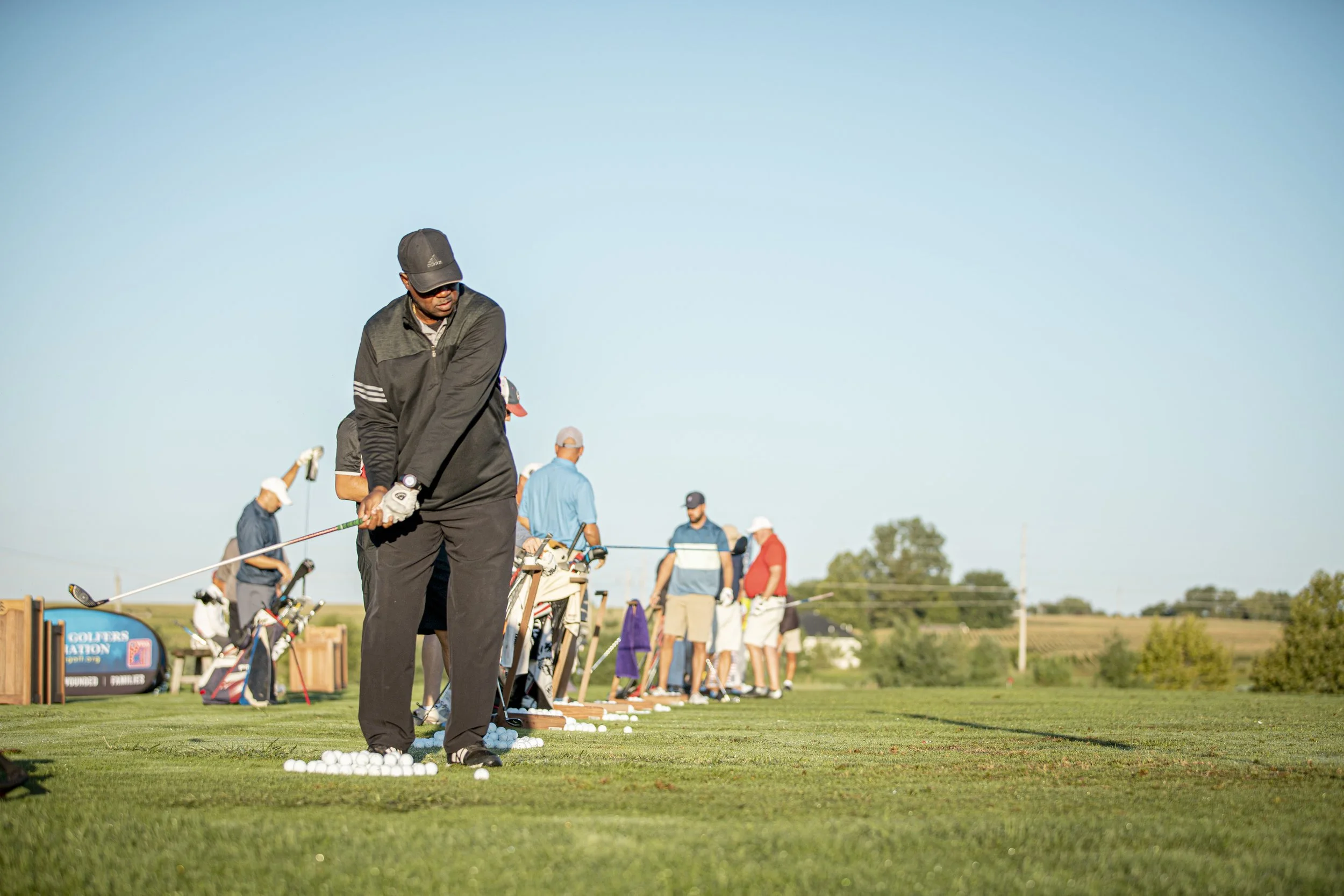 Golfers warm up on the driving range before a golf fundraiser.