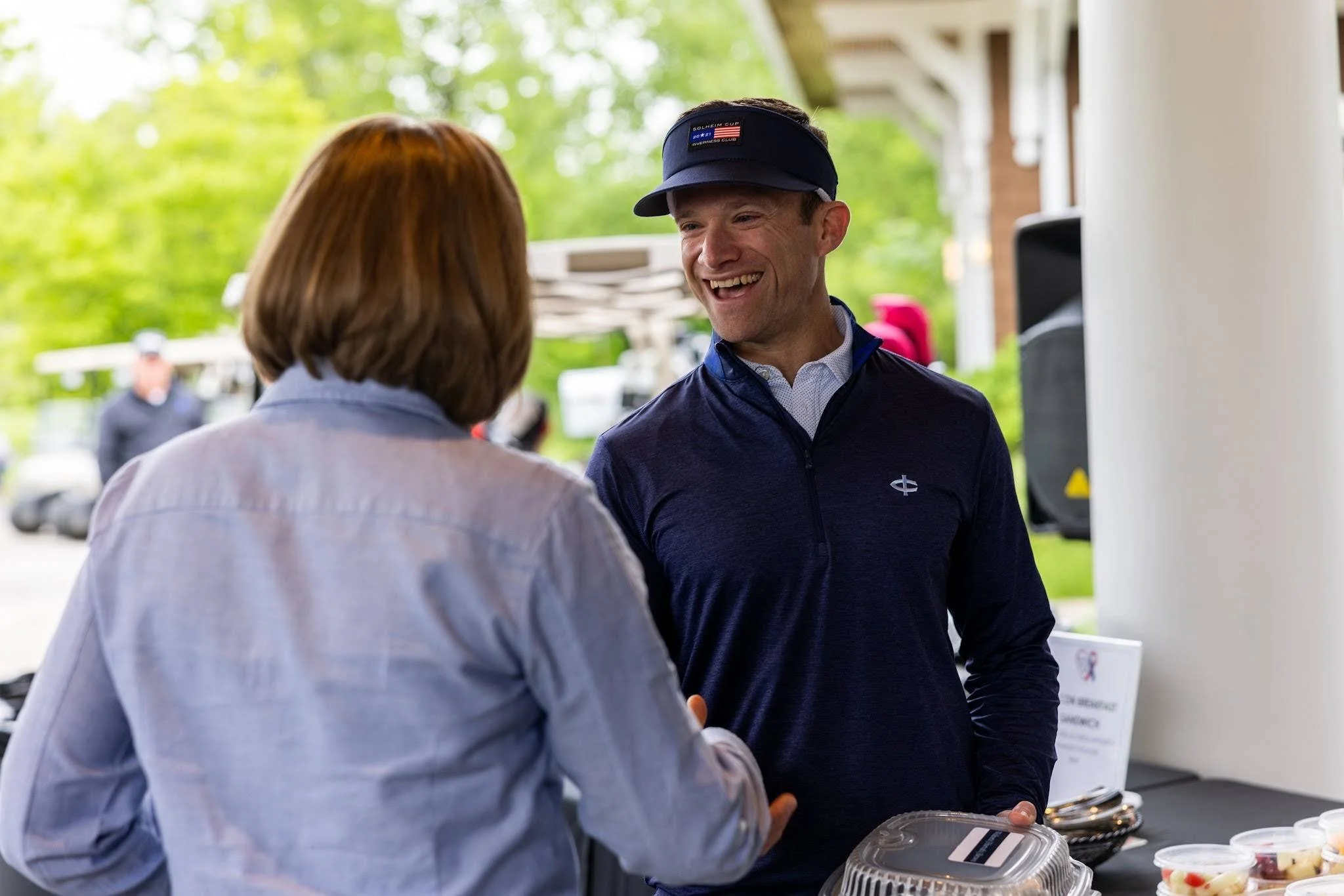 A man and a woman shake hands sharing a mission moment at a charity golf tournament.