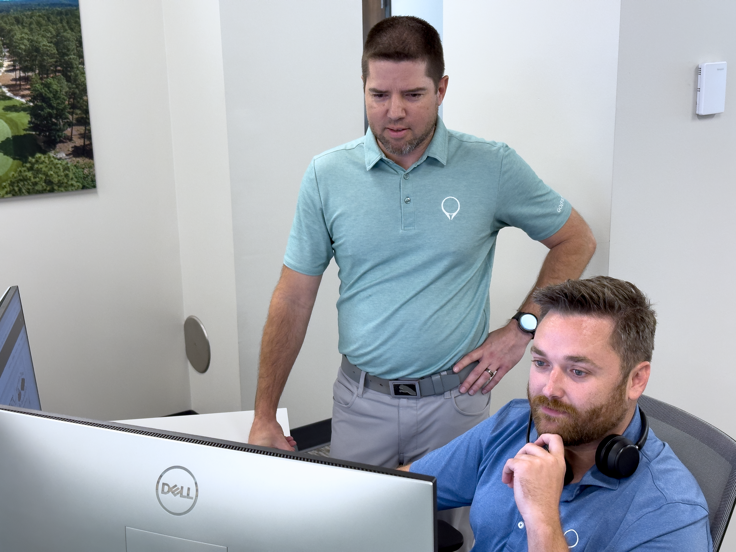 Two men look at a computer screen offering support as part of GolfStatus' tournament management software.