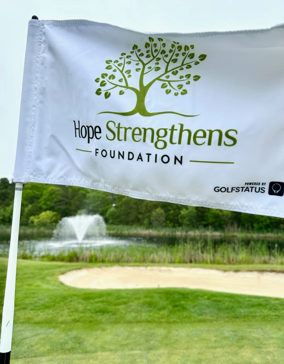 An image of a white custom golf pin flag with the Hope Strengthens Foundation logo.