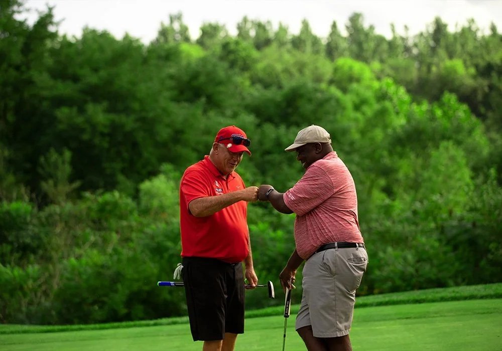 Two golfers fist bump at a charity golf tournament.