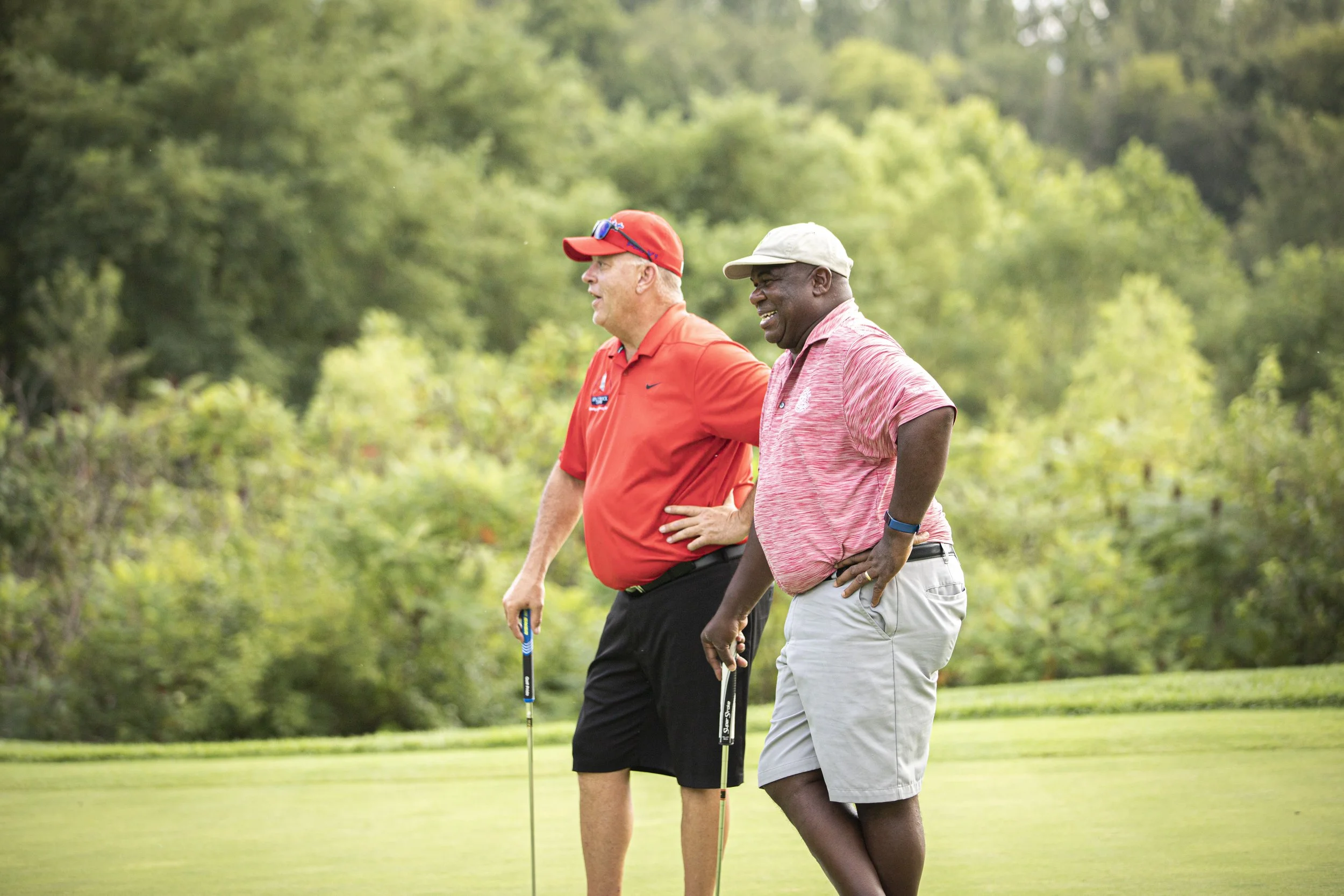 Two male golfers stand on the golf course during an alternate shot golf tournament format event.