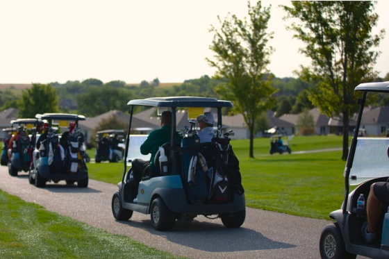Golfers drive in golf carts at at charity golf tournament, the top charity fundraising idea.