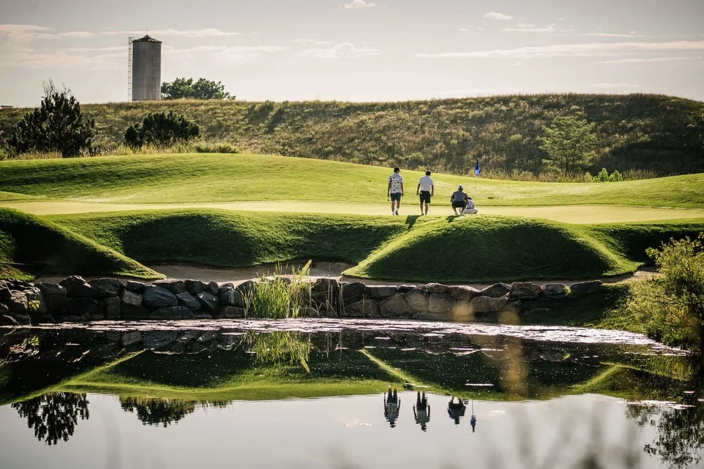 Golfers walk on a golf course on their way to participate in a putting contest, which is a classic golf tournament fundraiser idea.