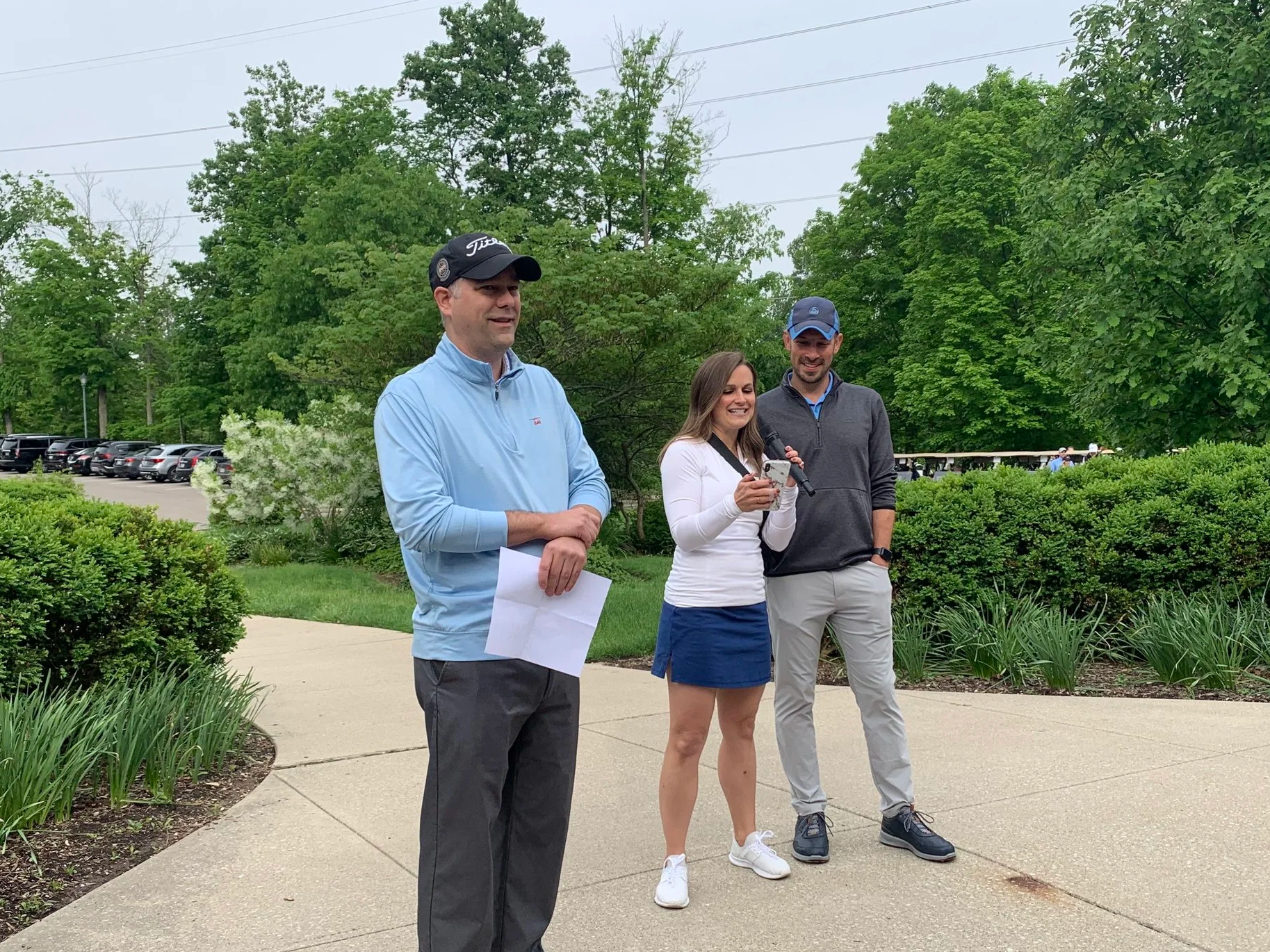 A golf tournament organizer speaks into a microphone to ask for donations at the start of the event.