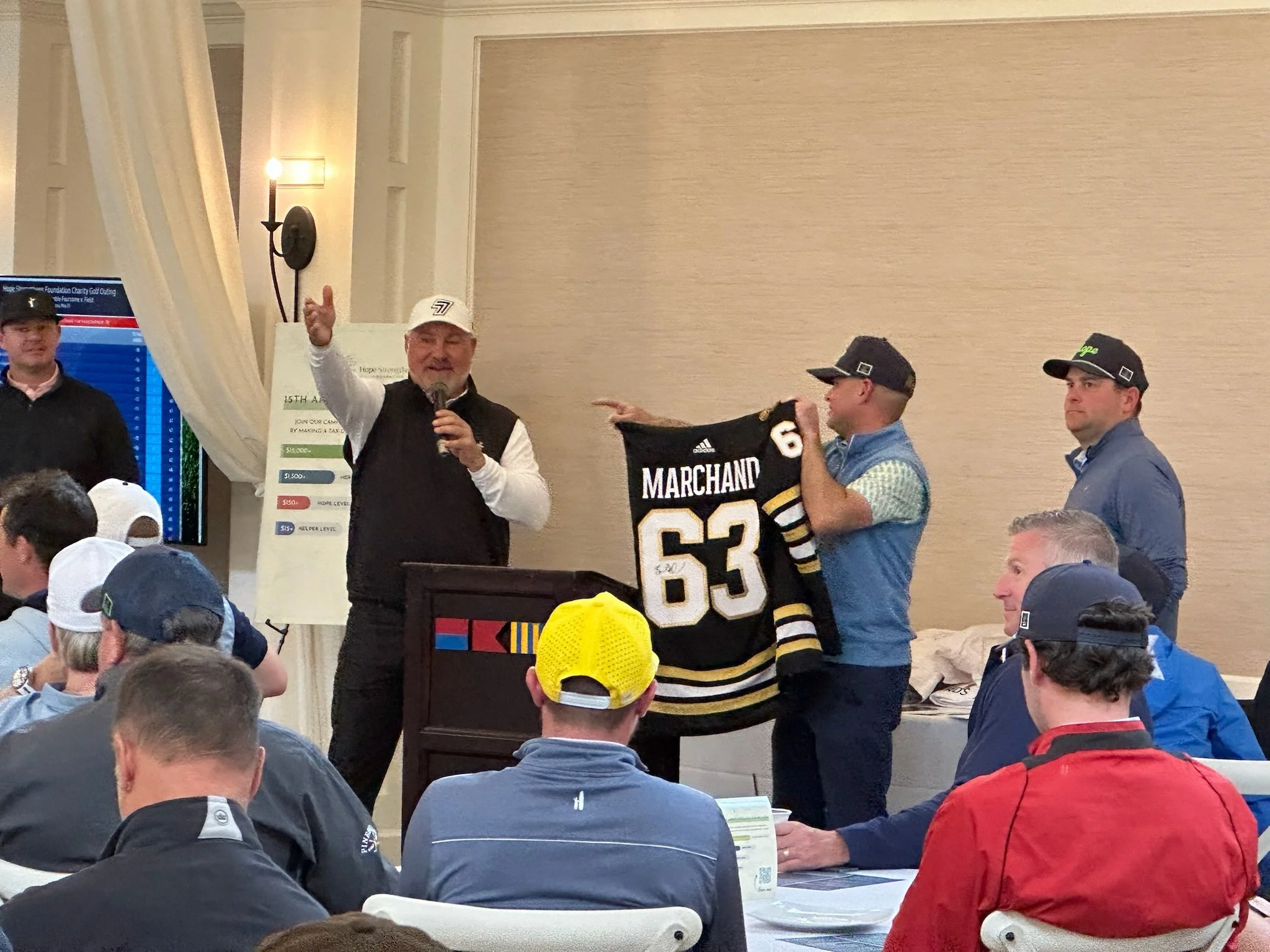 An auctioneer collects bids during a live golf charity auction.