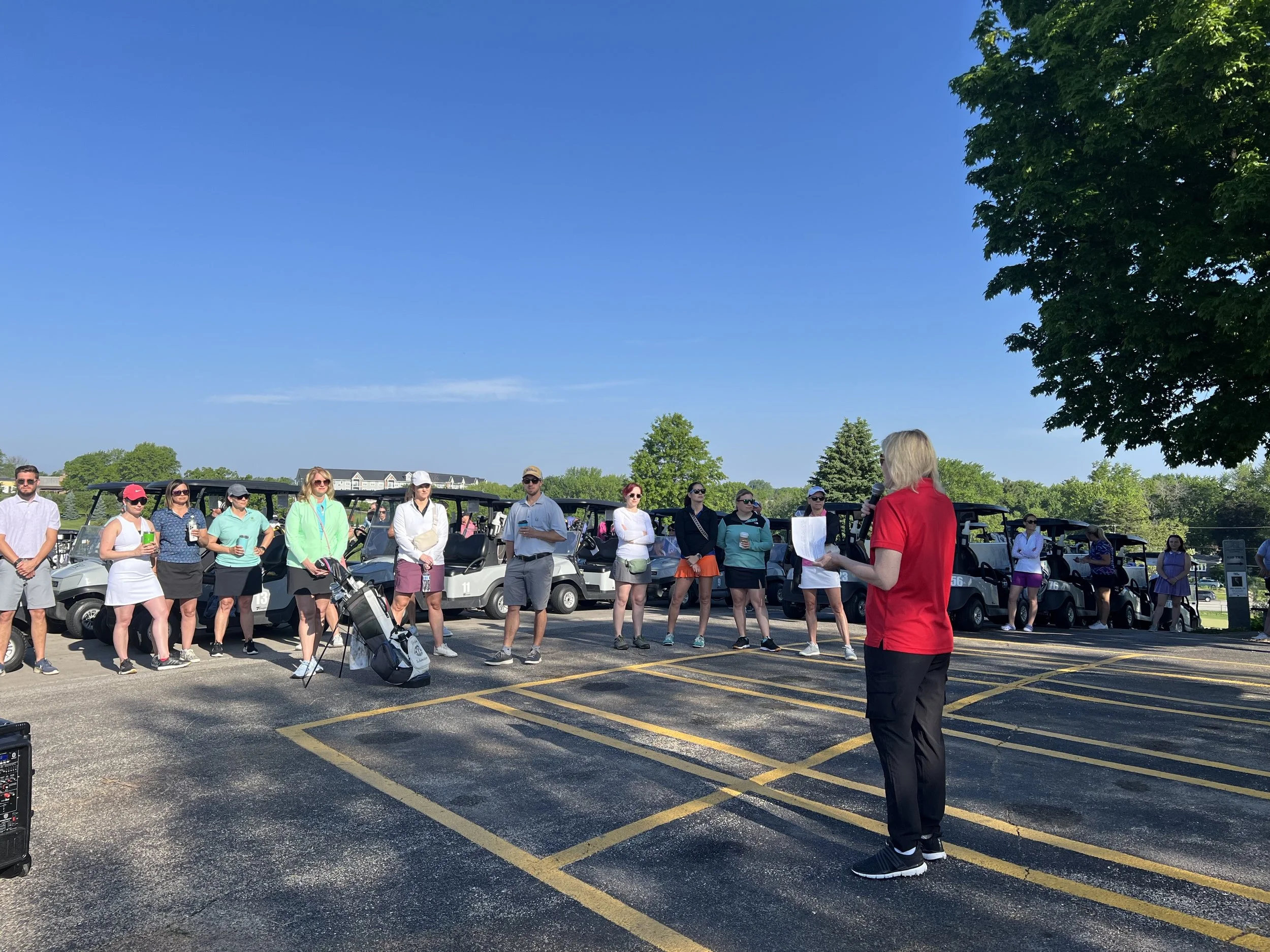 An organizer reviews the golf tournament format with players before the start of the event.
