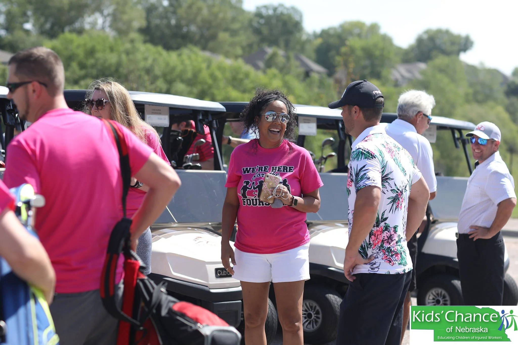 Golfers interact next to golf carts before the start of a charity golf tournament.