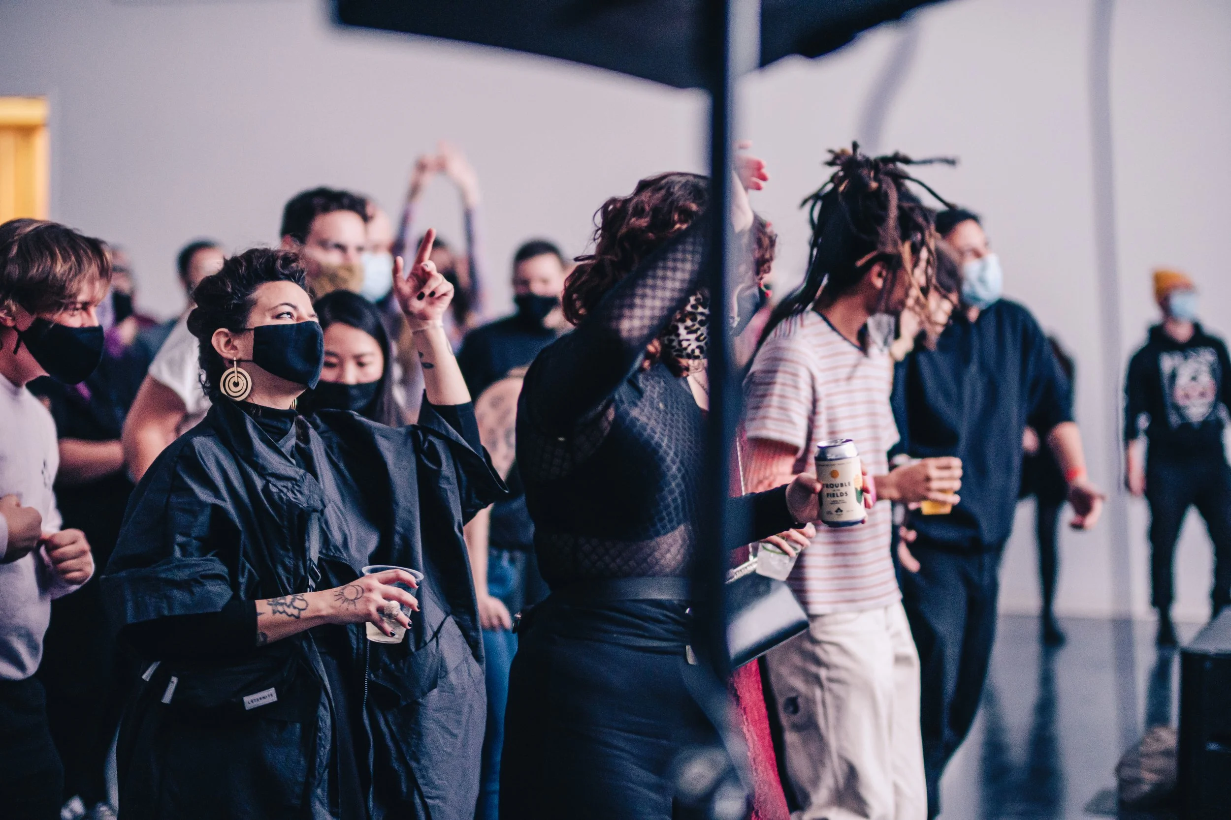 Masked Pique Audience members dance and gesture energetically while watching a performance.