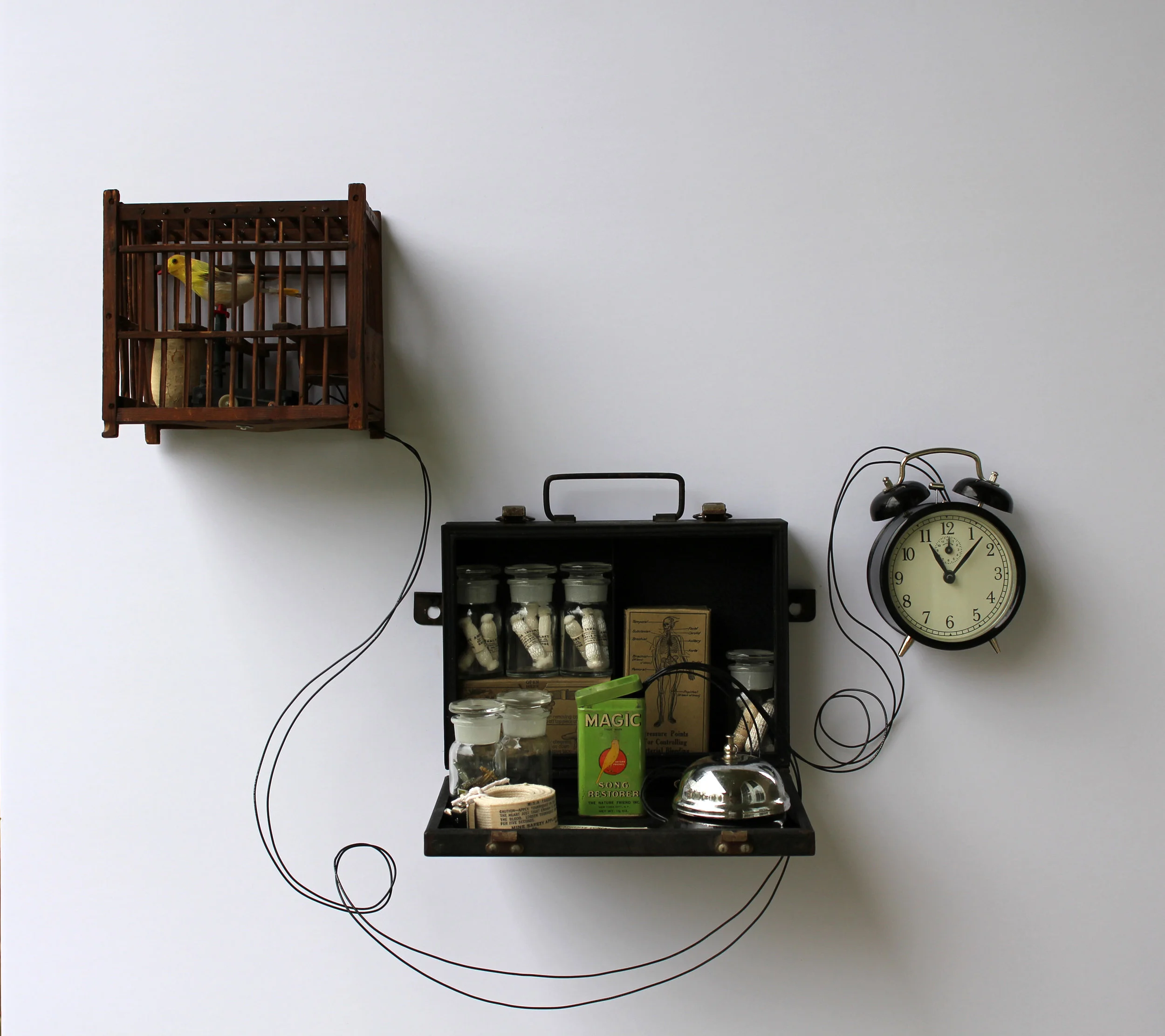 Magic Song Restorer, Antique miner's canary cage, mechanical bird, mining first aid kit, clock wires, bell and canary food tin. 2014 (In this kinetic sculpture, the bird moves and the clock chirps when someone rings the bell.)