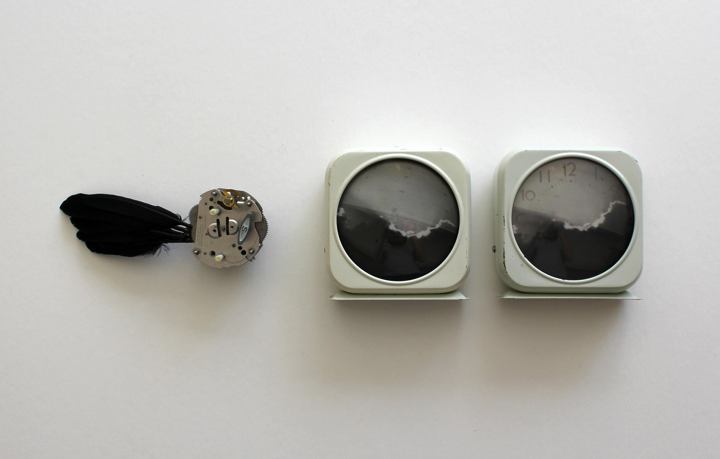 Black Wing, Dark Cloud, Vintage clocks, altered photos, feathers. (In this kinetic sculpture, the wing flaps twice each day for about 30 seconds.), 12 x 4 x 4 inches, 2013.