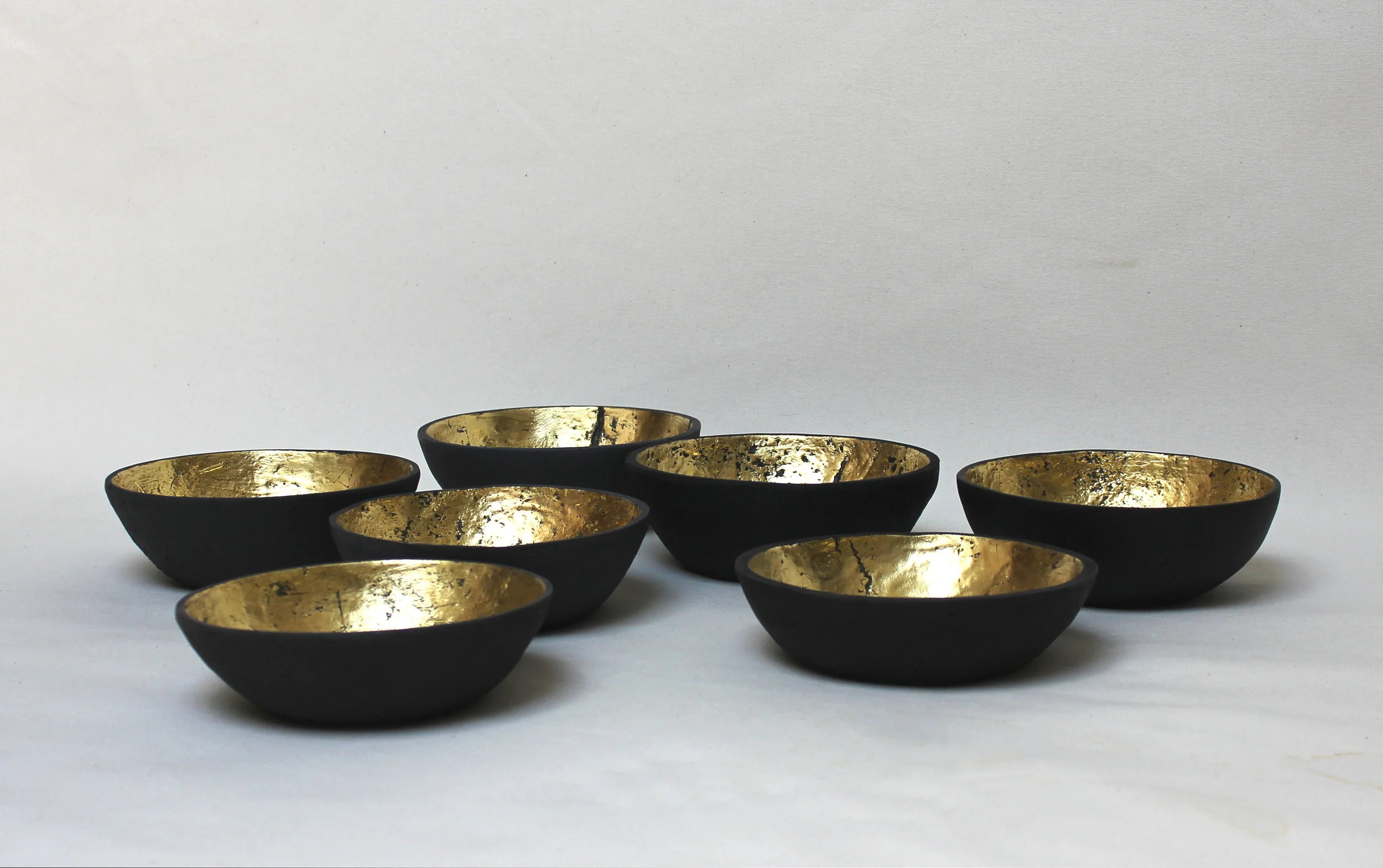 Seven Bowls, ashes, egg yolk, clove oil, beeswax, and gold leaf, 7 x 7 x 2.5 inches each, 2012.