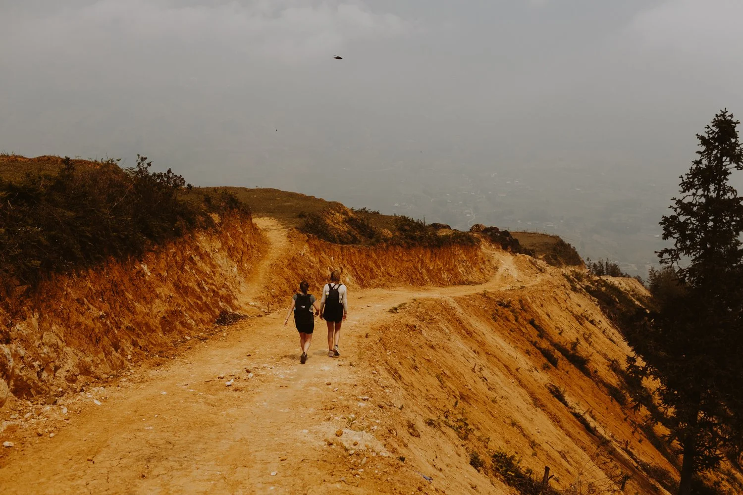 Adventurous hikers on a dusty orange trail, edited with the M5 Moody Earth preset for rugged landscape photography.