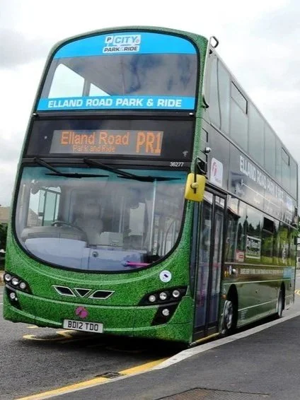 Green double-decker bus on a city street, displaying route information for Elland Road Park & Ride with a digital sign indicating this is the priority route.