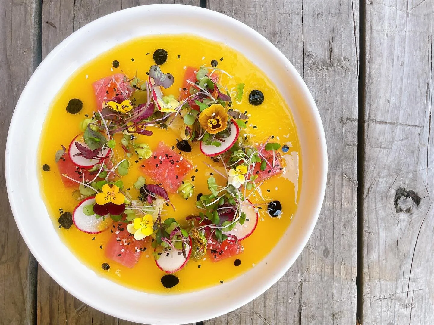 The newest ahi tuna crudo has a mango gastrique, green chiles, radish, avocado purée, and sesame seeds