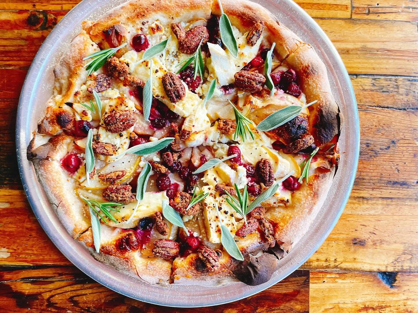 The Grim Re-pear sourdough flatbread only available this week! 🍐 💀 
.
Pears, Brie cheese, cranberries, goat cheese, candied pecans, hot honey, garlic oil, white balsamic reduction, all the sage, and other herbs.