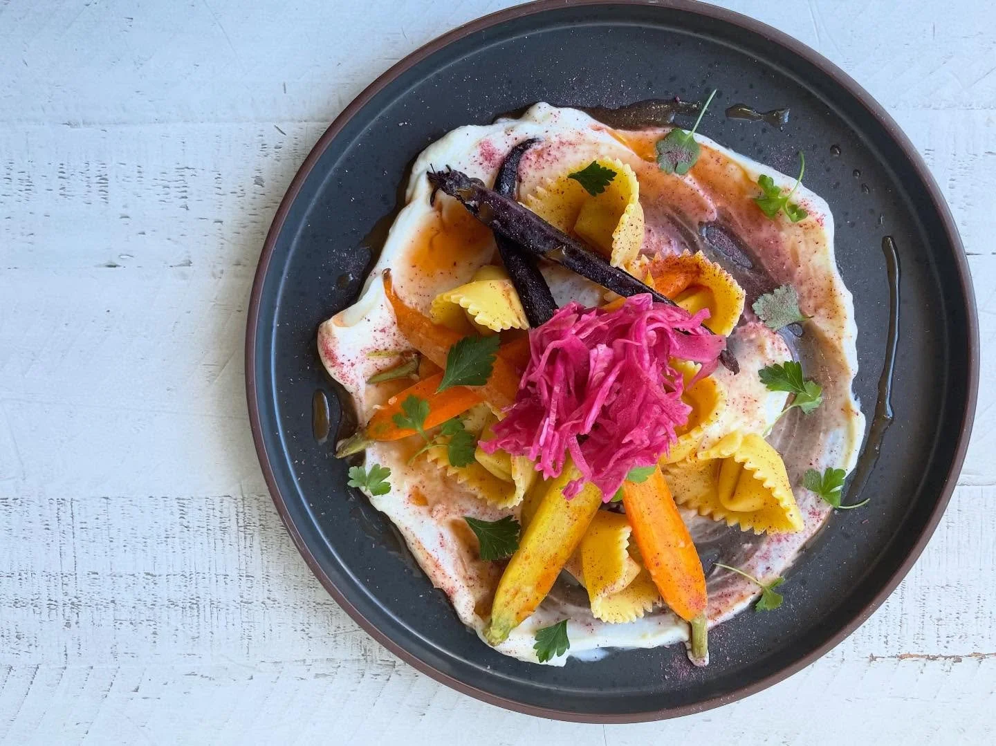 Carrot cappellacci with carrot and gochujang filling, miso roasted rainbow carrots, carrot gastrique, honey ricotta, pickled red cabbage, hot honey, parsley, kraut dust 🥕