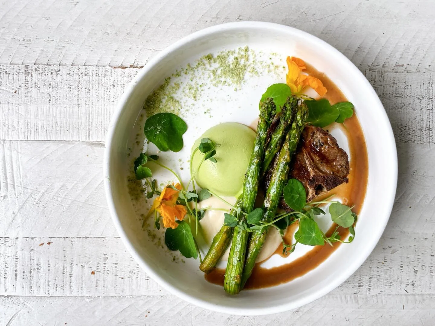 Lamb loin chop with roasted asparagus, cauliflower pur&eacute;e, savory pea panna cotta, red wine beef demi sauce, pea dust, nasturtium, pea shoots