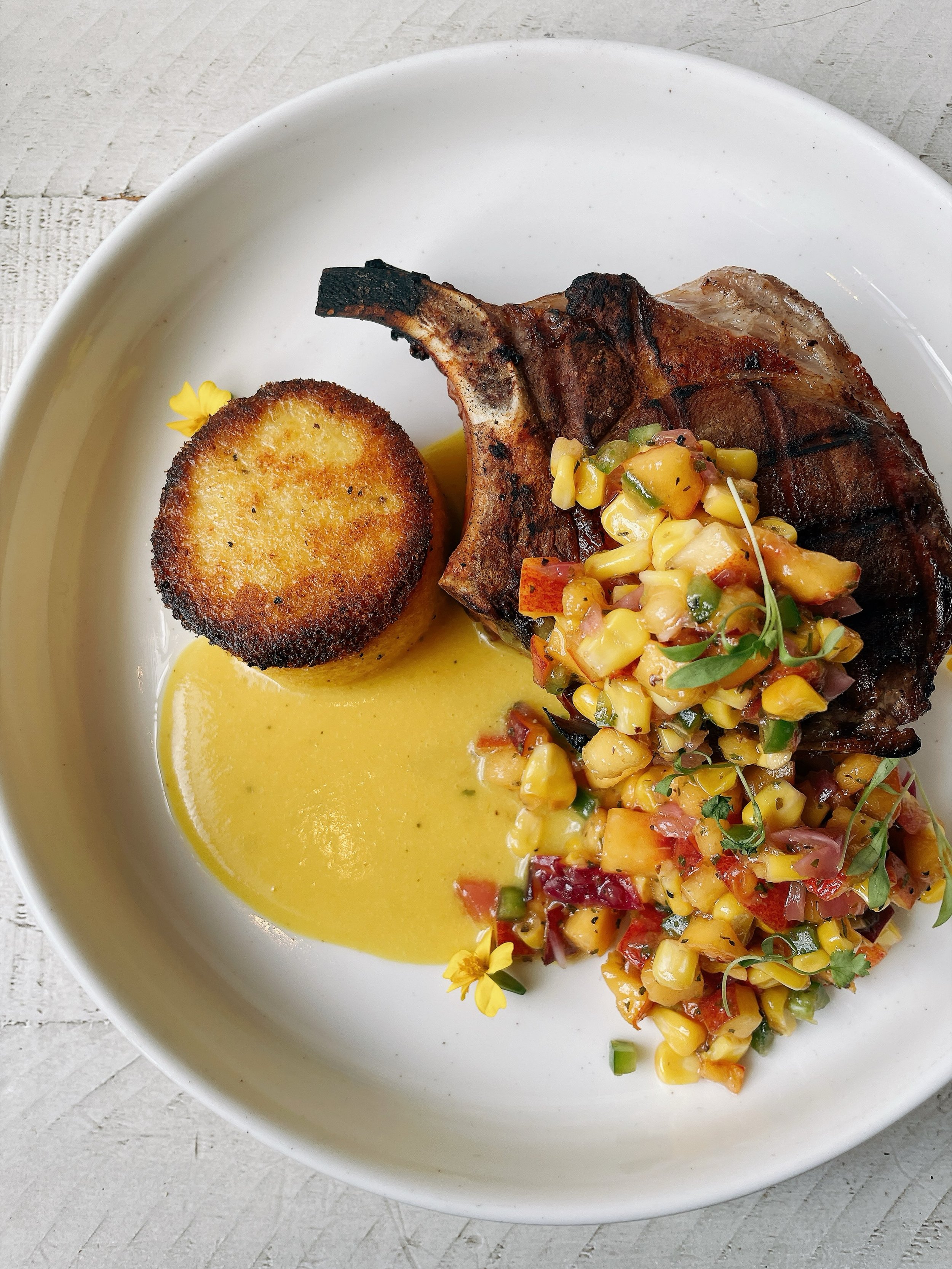 Pork rib chop with peach corn salsa, peach bourbon sauce, crispy polenta cake. On the menu now!