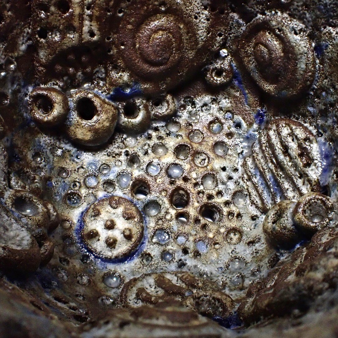 An image of the interior of a black stoneware Rockpool Vessel with the blue cobalt oxide and porcelain slip bleeding out from behind the small encrusted details.  My experiments with different clays and oxides have provided an endless rabbit hole for