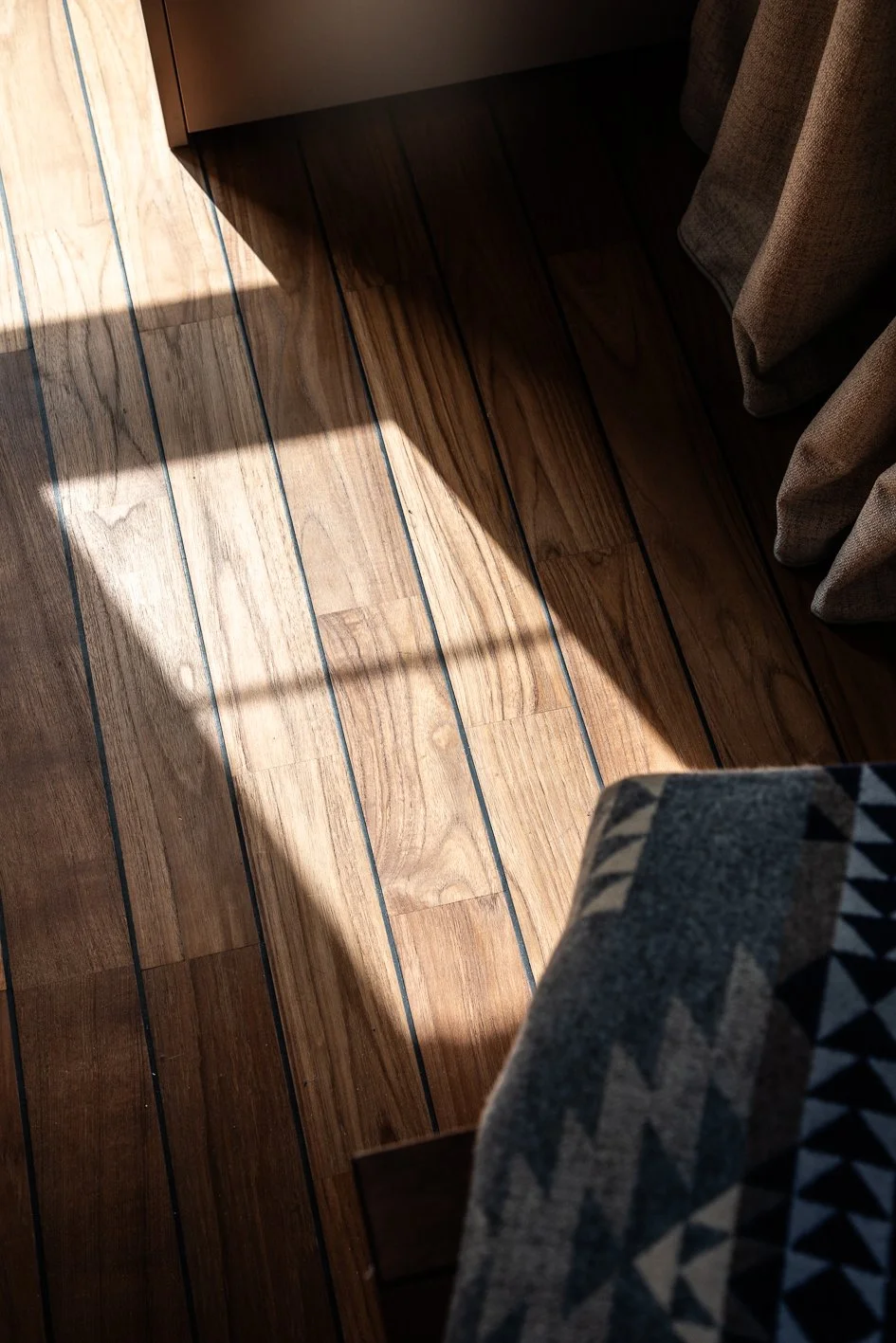 photographie de détail sur un parquet de style pont de bateau mis en évidence par un rayon de soleil - architecture d'intérieure en Brabant Wallon par Stéphanie Asta