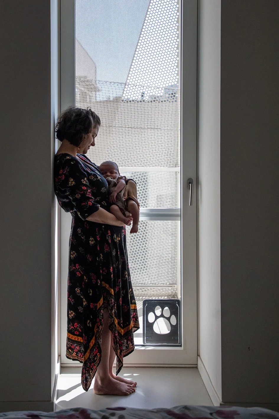 Séance photo naissance à domicile d’une maman avec son bébé, dans une belle lumière naturelle à Bruxelles