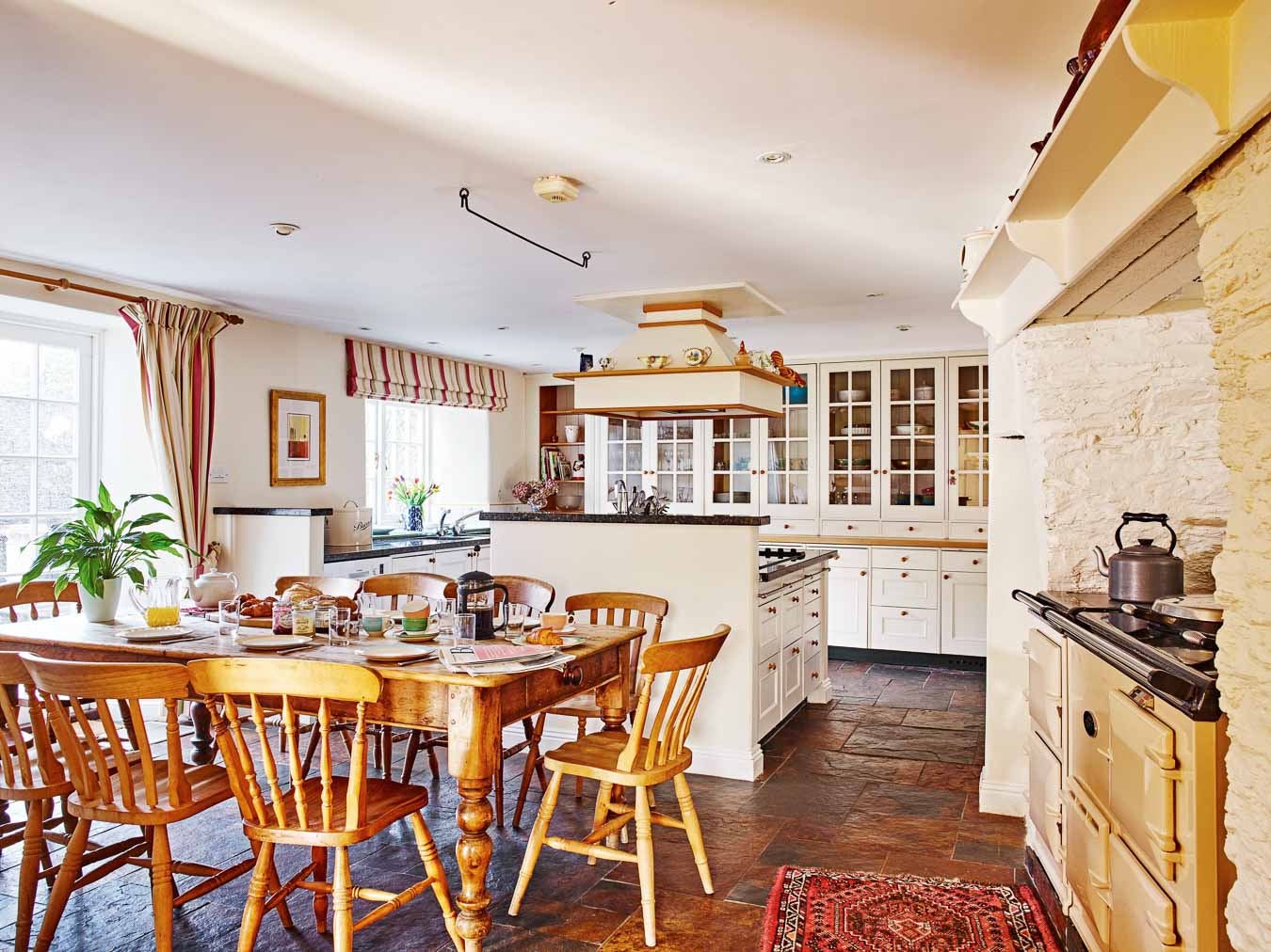 The large and homely country style kitchen with rustic table, Aga and generous built in cupboards in Flear House. 