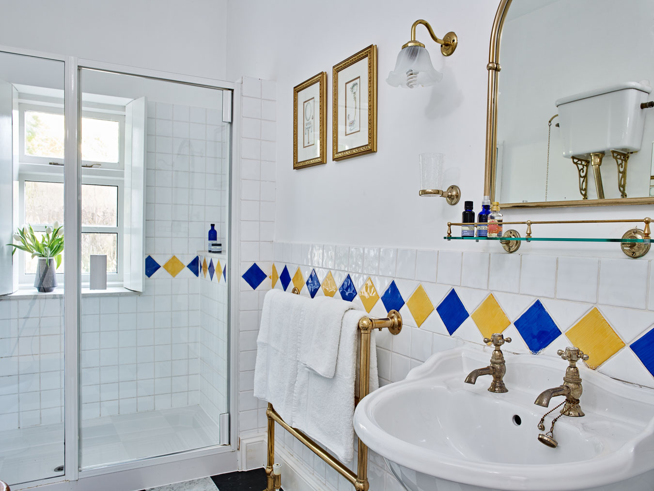 The near by bathroom that serves the twin rooms in Flear House. It has gold accessories and a fun Harlequin tile on the wall's and floor. 