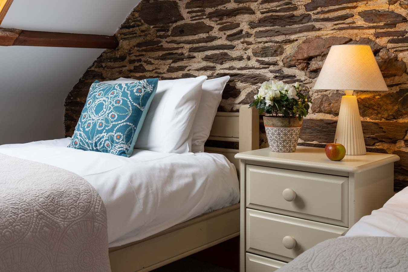 The charming twin room in Cartwheel cottage with exposed brick and soft tones at Flear Farm. 