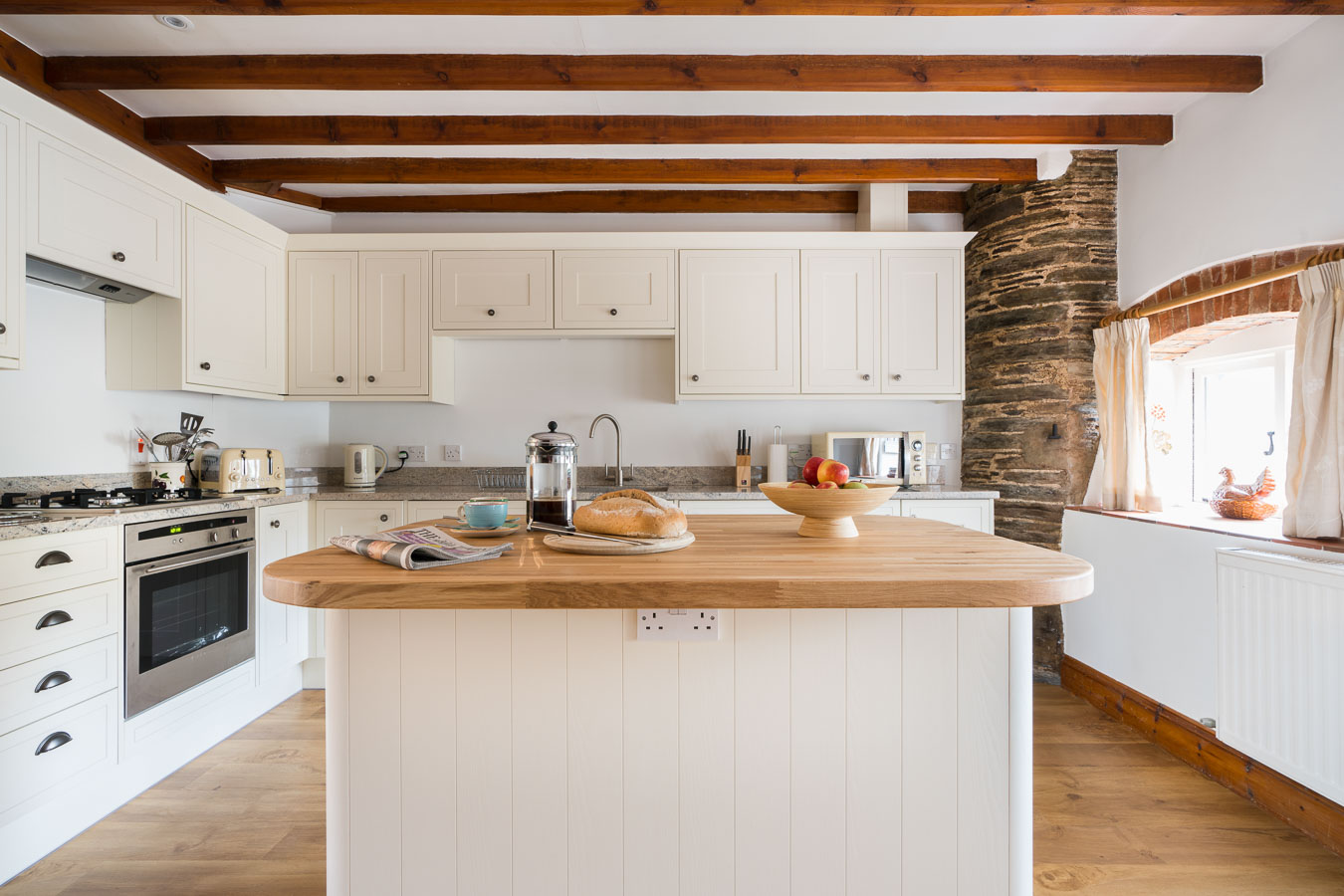 The light and modern kitchen in Cartwheel cottage Flear Farm with its oak topped  island and soft toned granite  worktops behind.