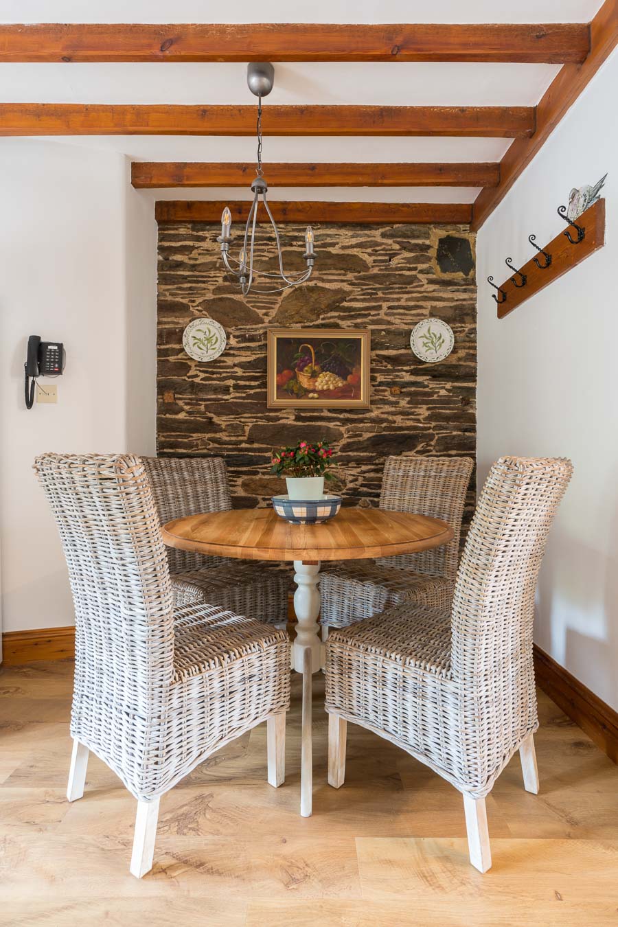 The dining table for four in Cartwheel cottage with wicker chairs and exposed brick work behind.  